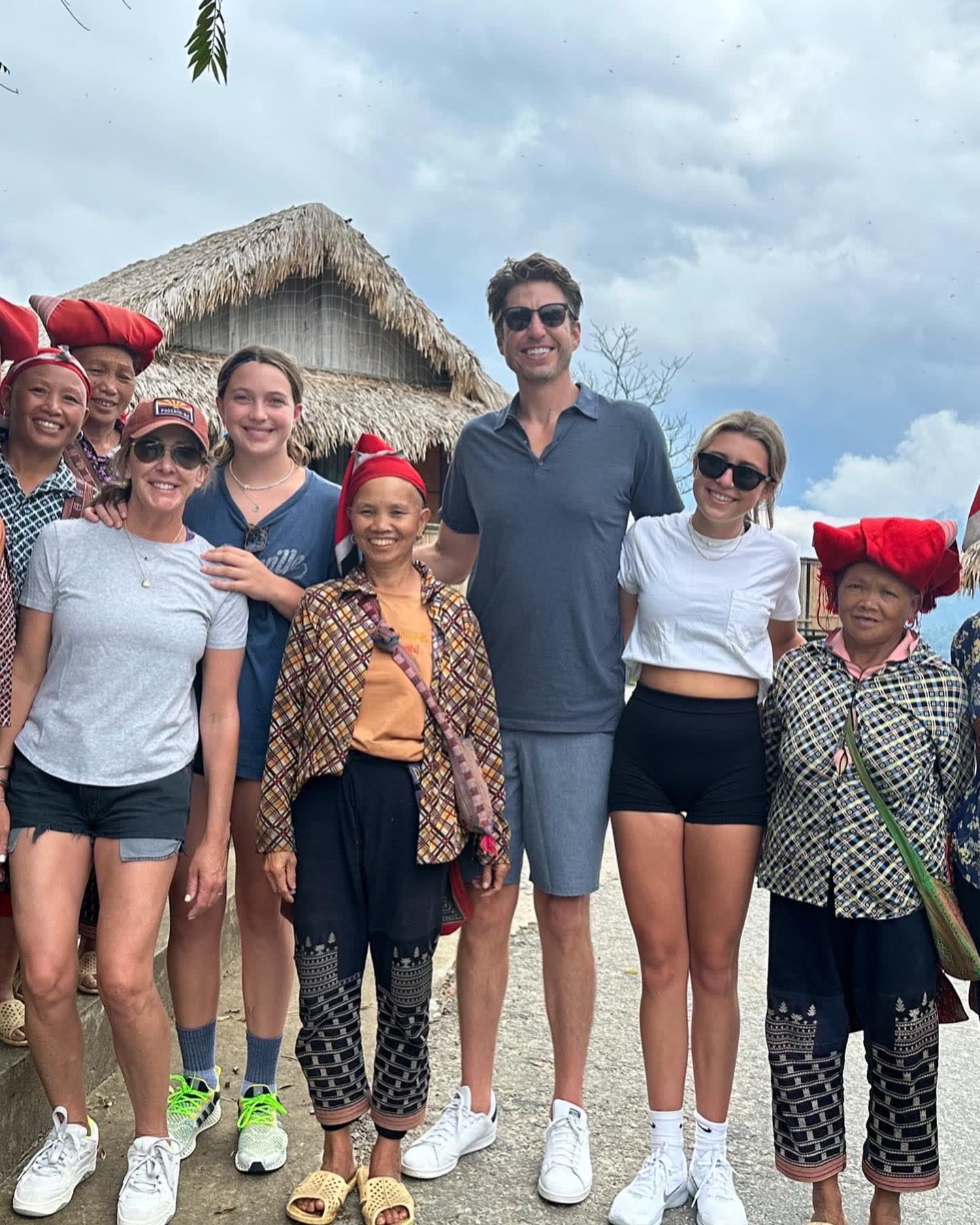 A group posing with local women wearing red head accessories