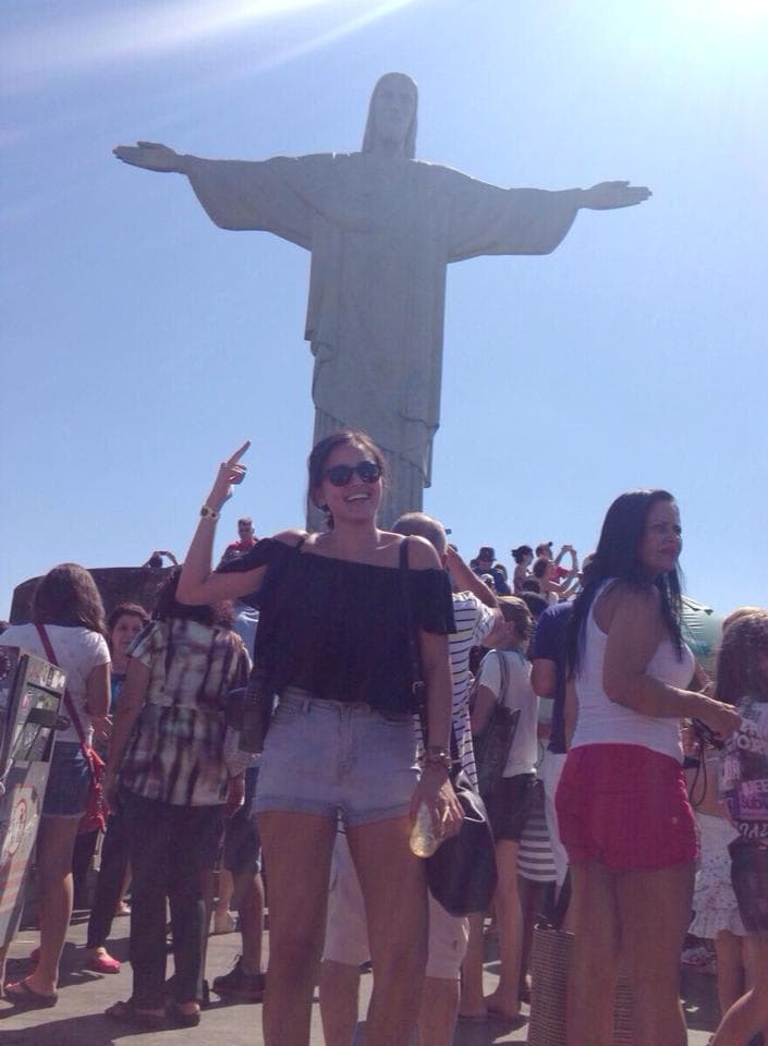 Carissa standing in front of and pointing to the Christ the Redeemer statue in Rio.