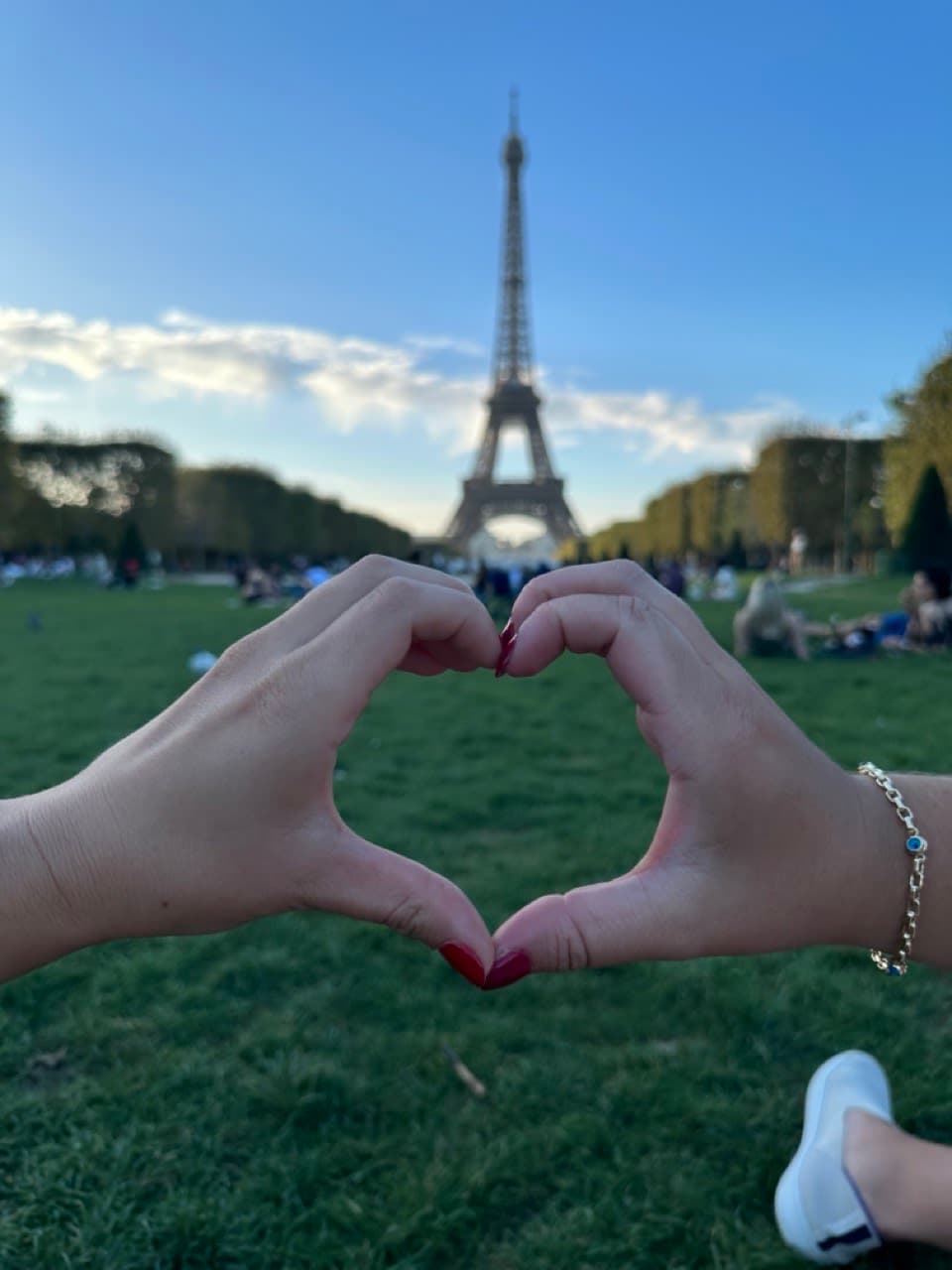 Making a heart sign with hands in front of Eiffel Tower