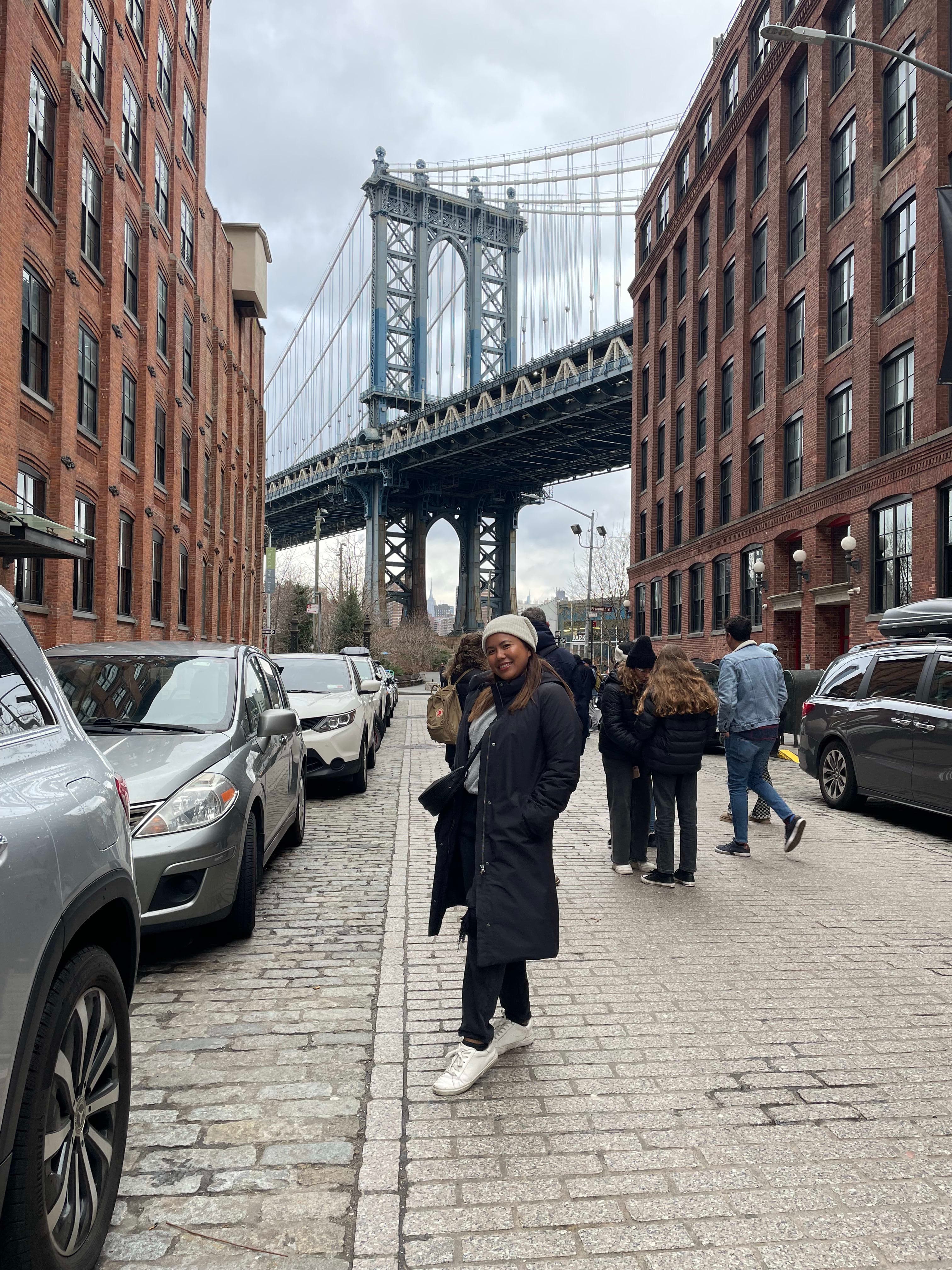 Posing for a photo on the street with a bridge in the background