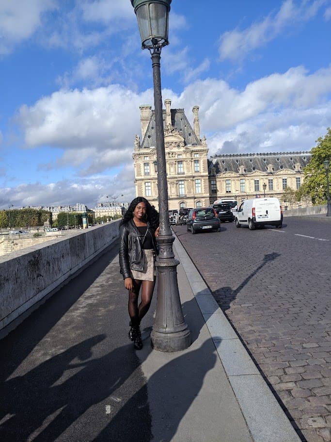 Posing for a photo on the street leaning to a light post