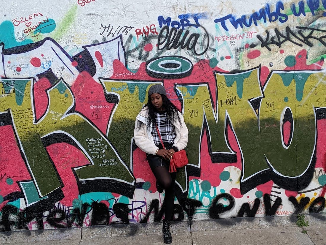 Posing for a photo standing leaning to a graffiti wall