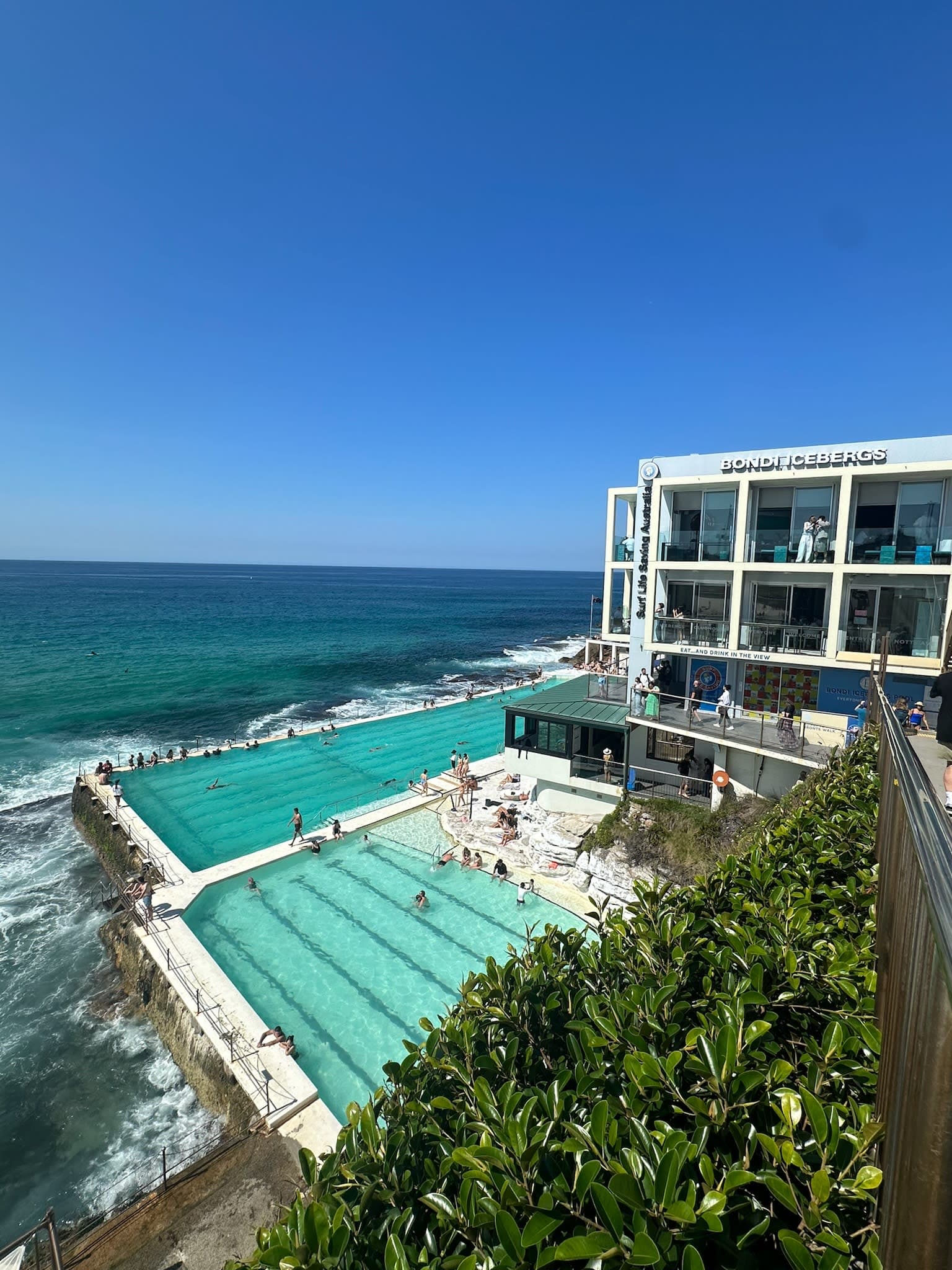 A view over multiple hotel pools that end just at the edge of the ocean.