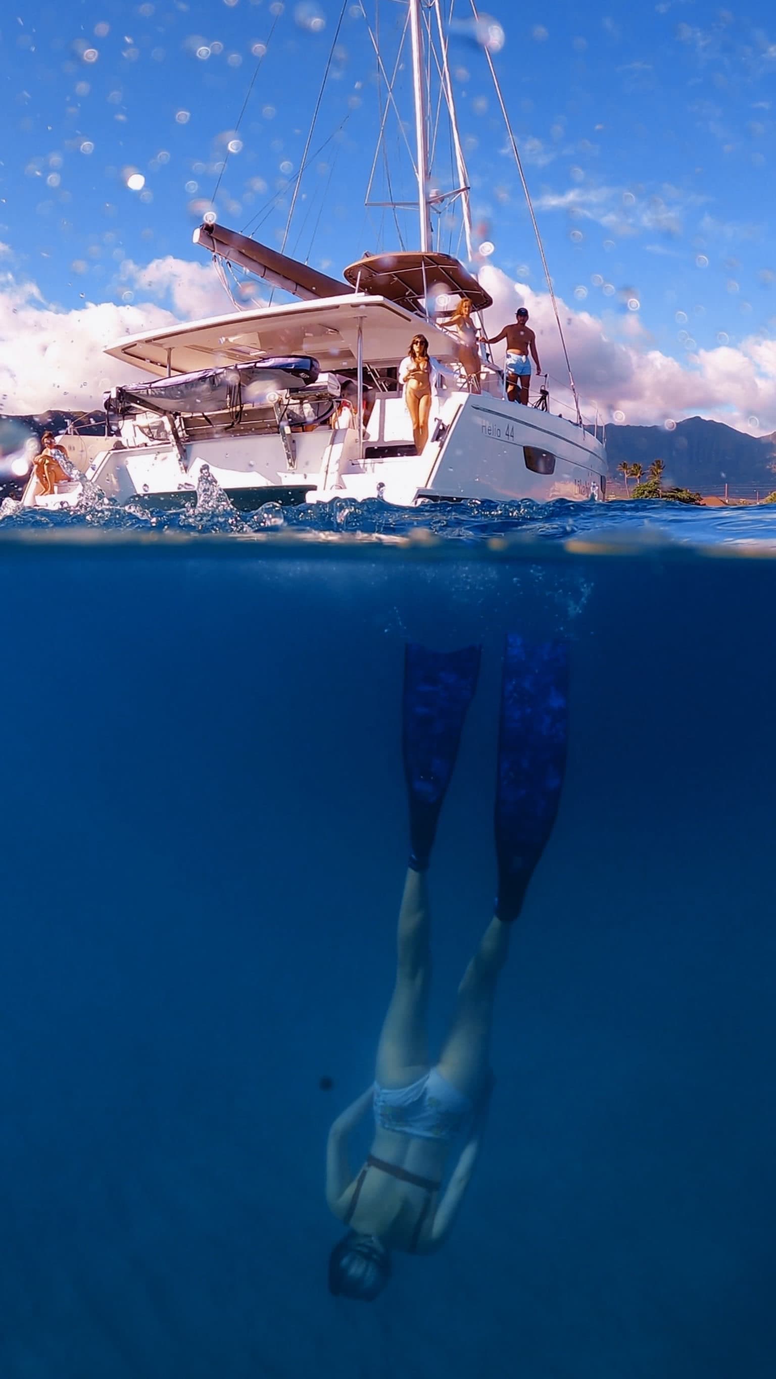 A person free diving in the sea with flippers on as a white boat floats on the water's surface.