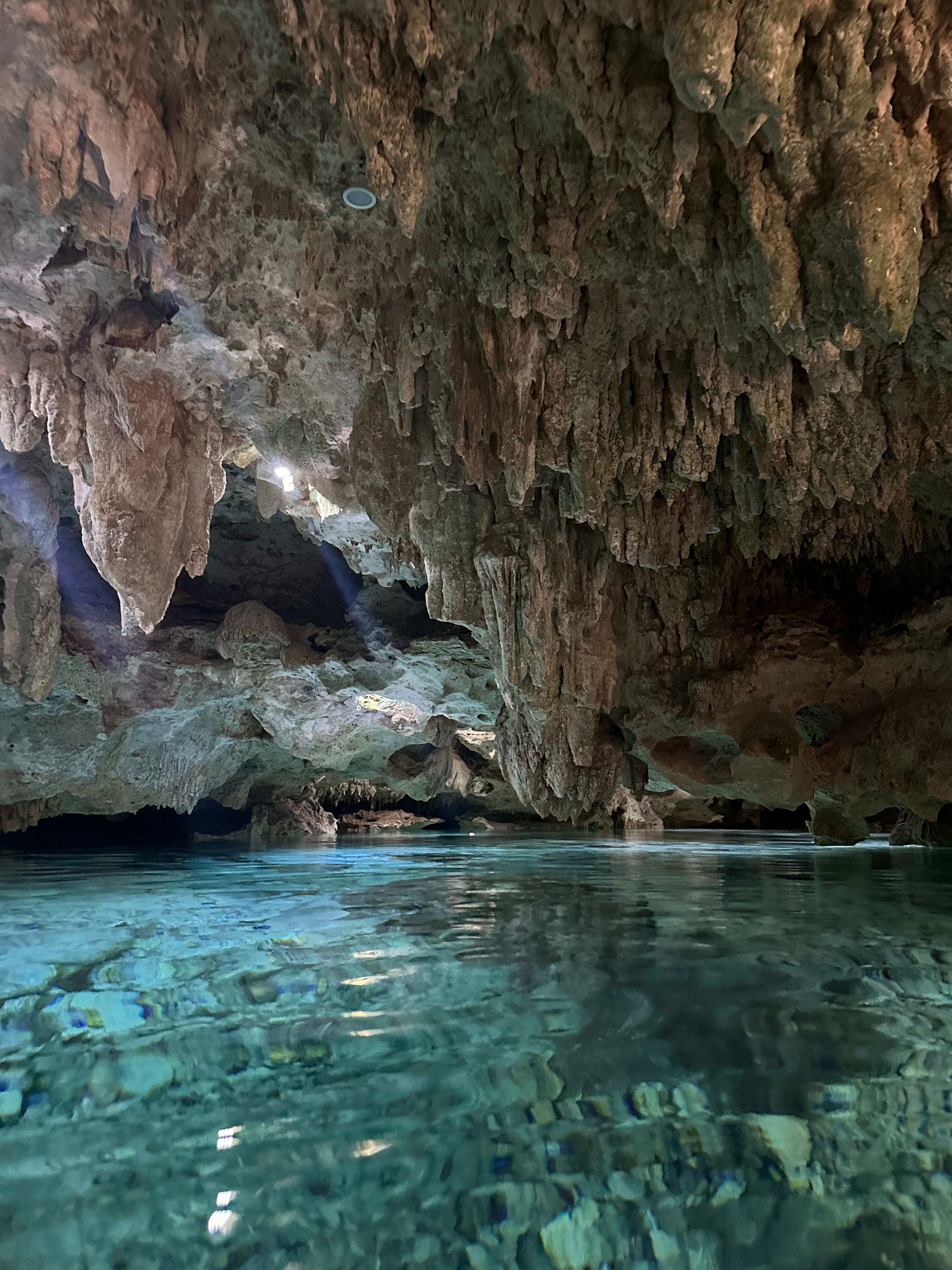 The interior of a cave with clear turquoise water and hanging rock formations