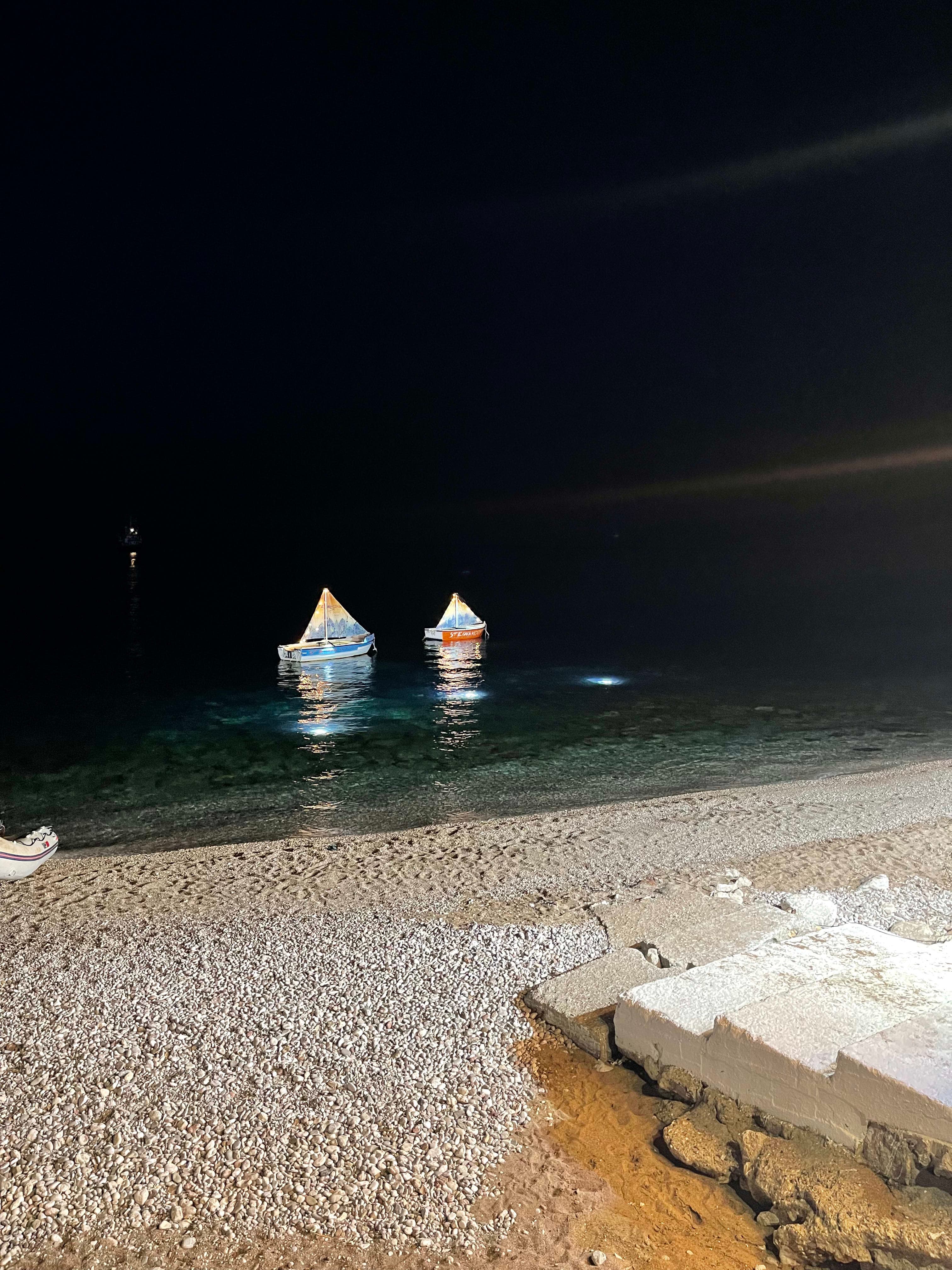 Miniature boats floating on the sea at night