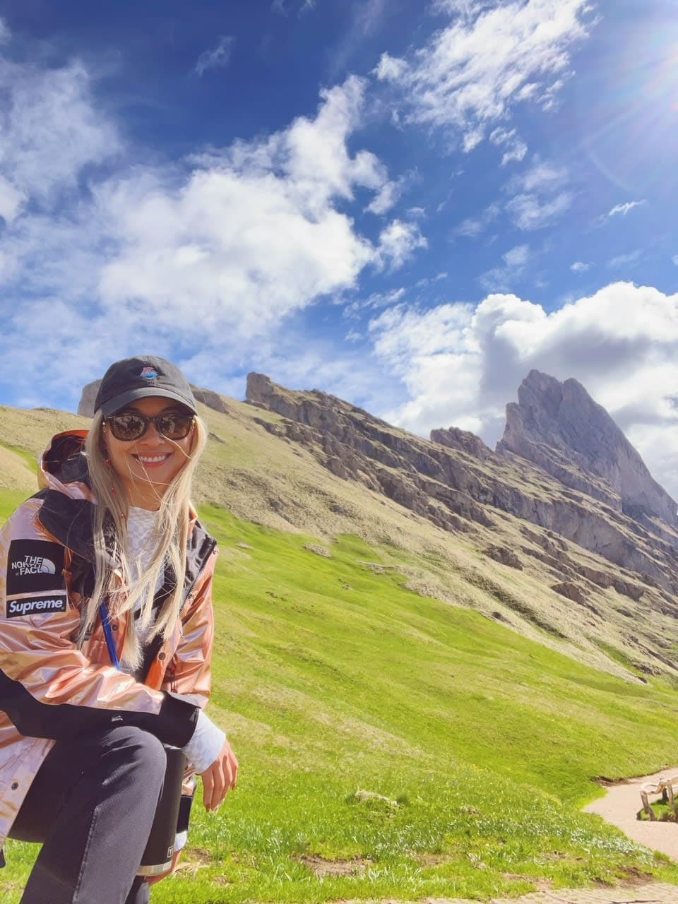 Noemi posing on a hike with mountains and greenery in the distance