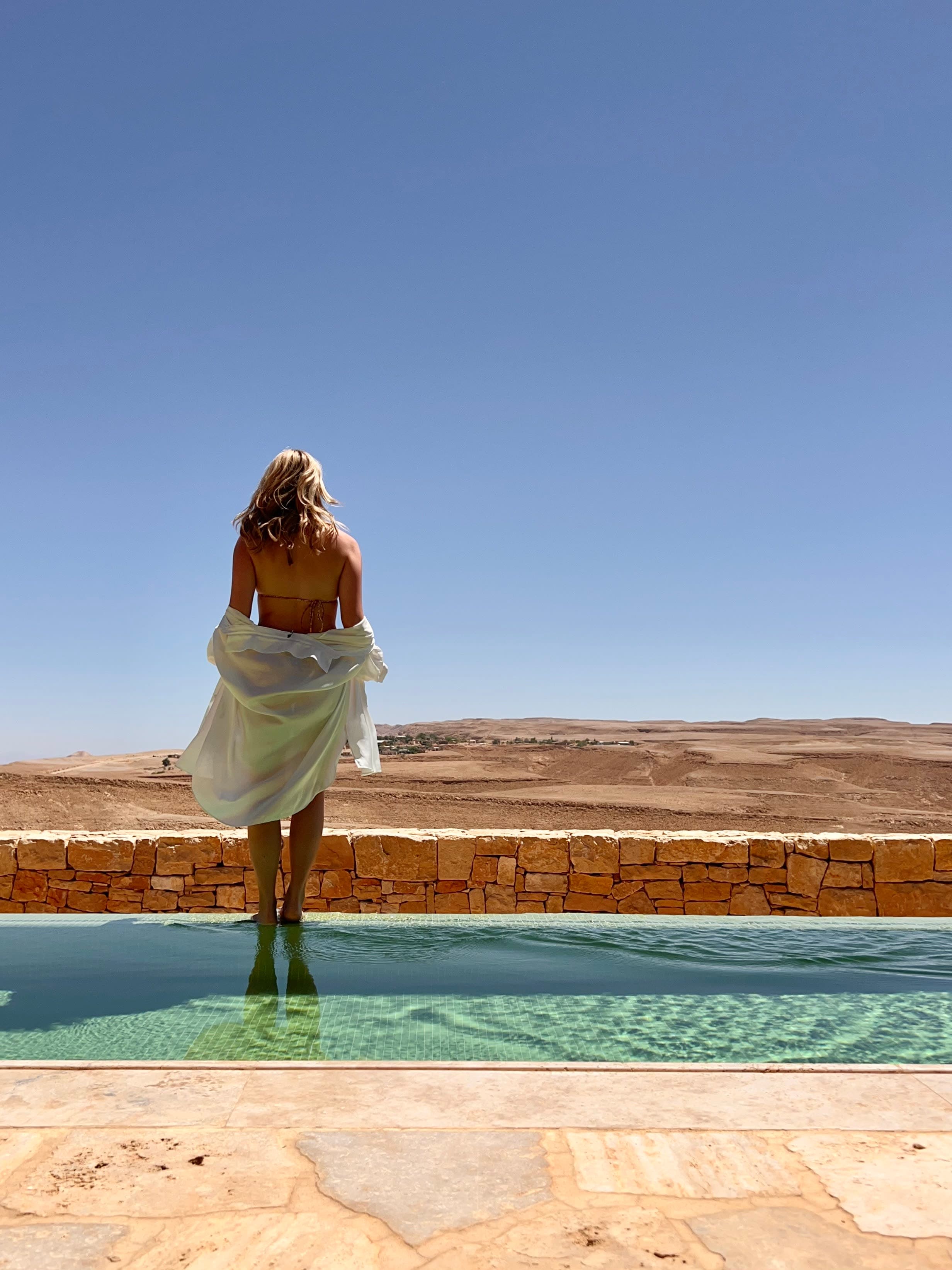 Alice standing alongside pool with desert view