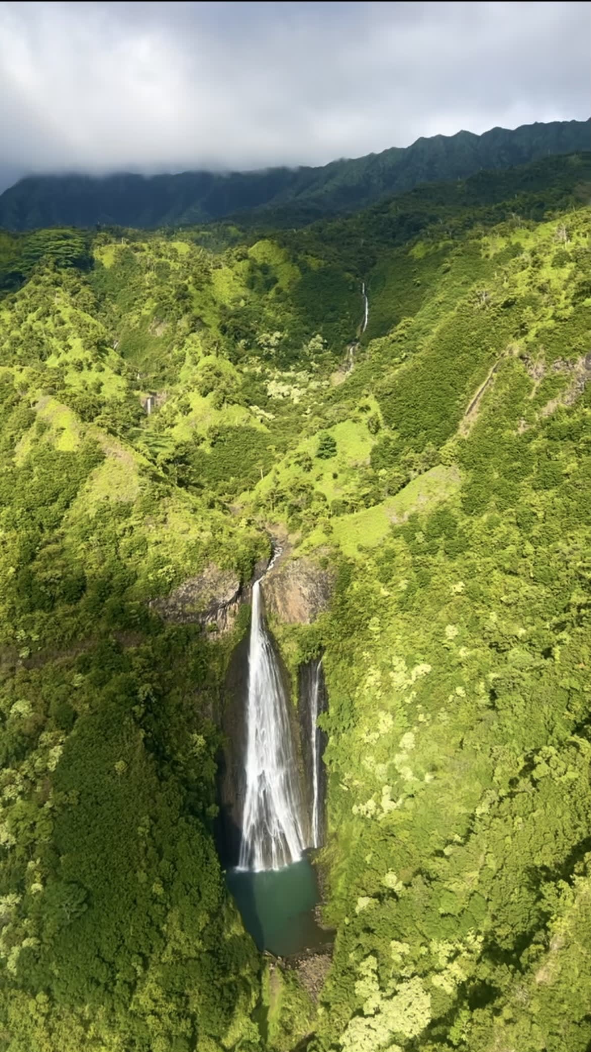 A view of a beautiful lush green valley with a waterfall