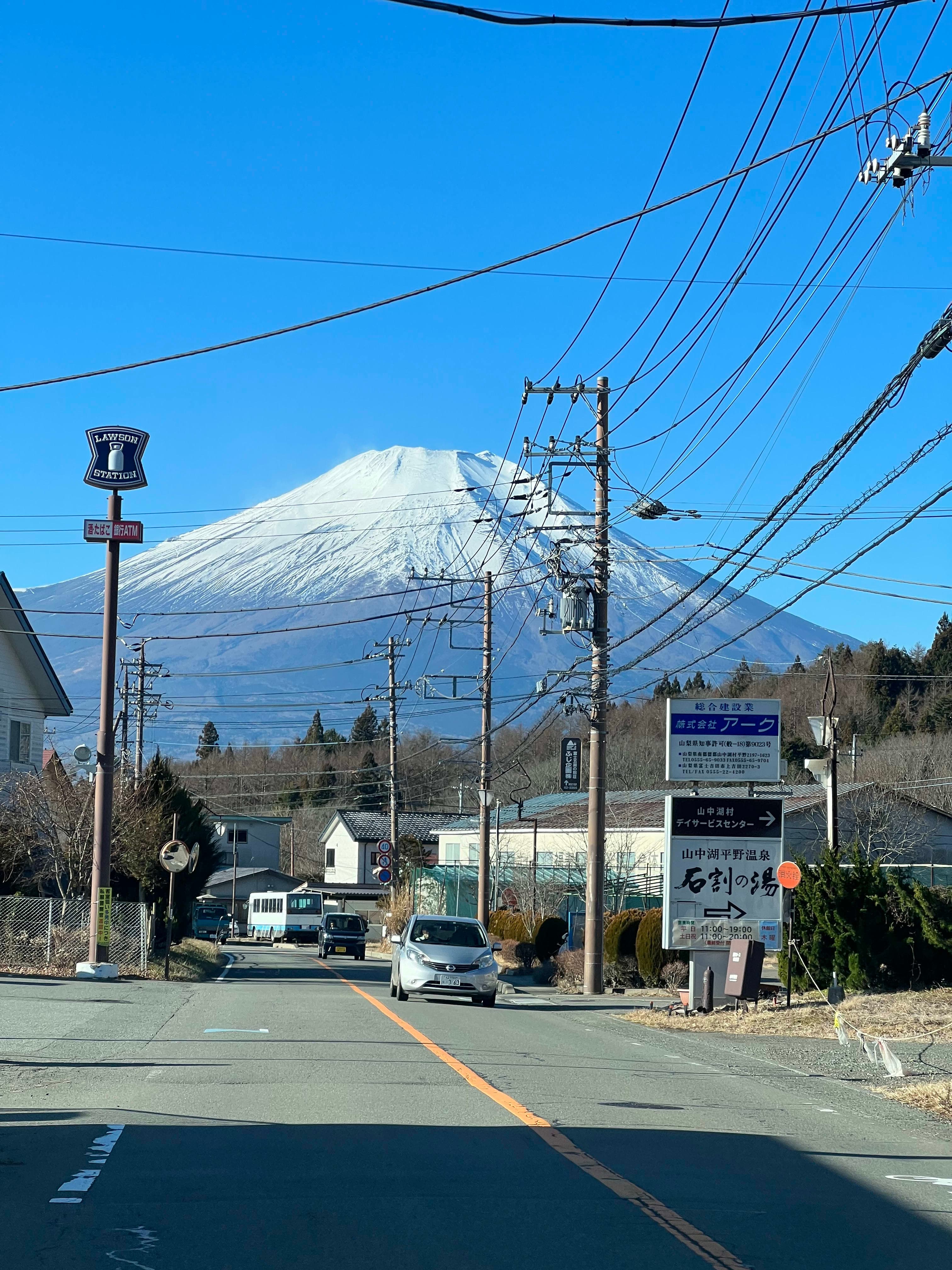Beautiful view of Mount Fuji from the road with cars driving, street lamps and signage