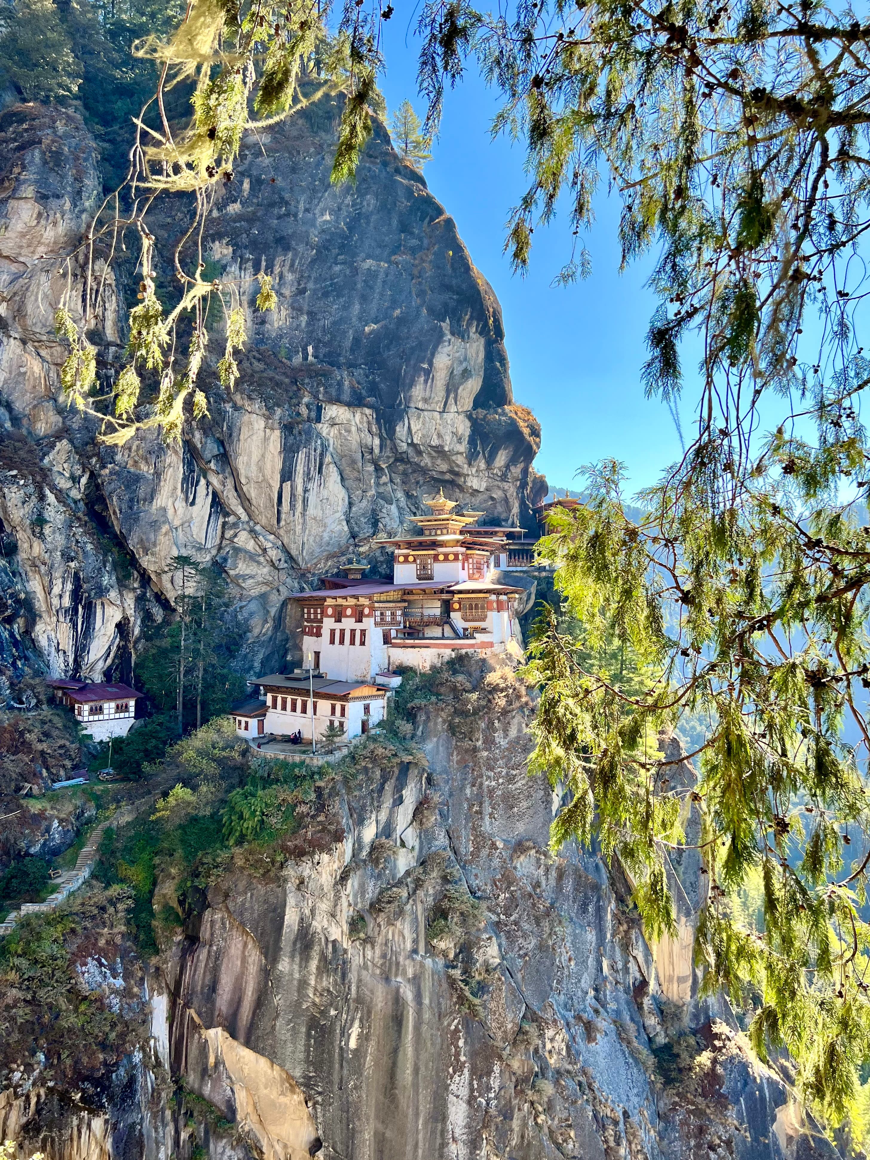 View of a temple with gold, red and white features high on a cliffside