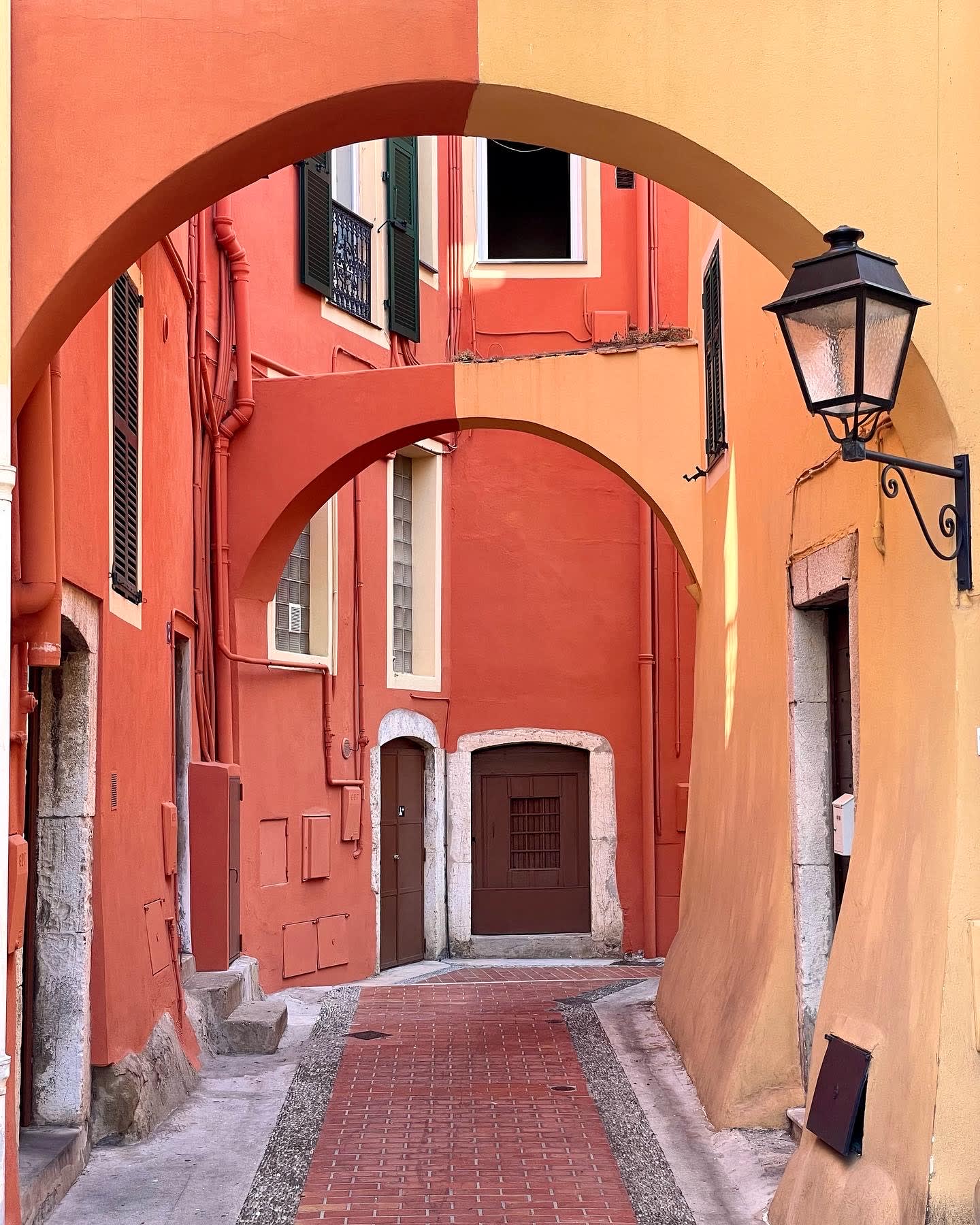 View of red and yellow colored buildings in a narrow street with two arches
