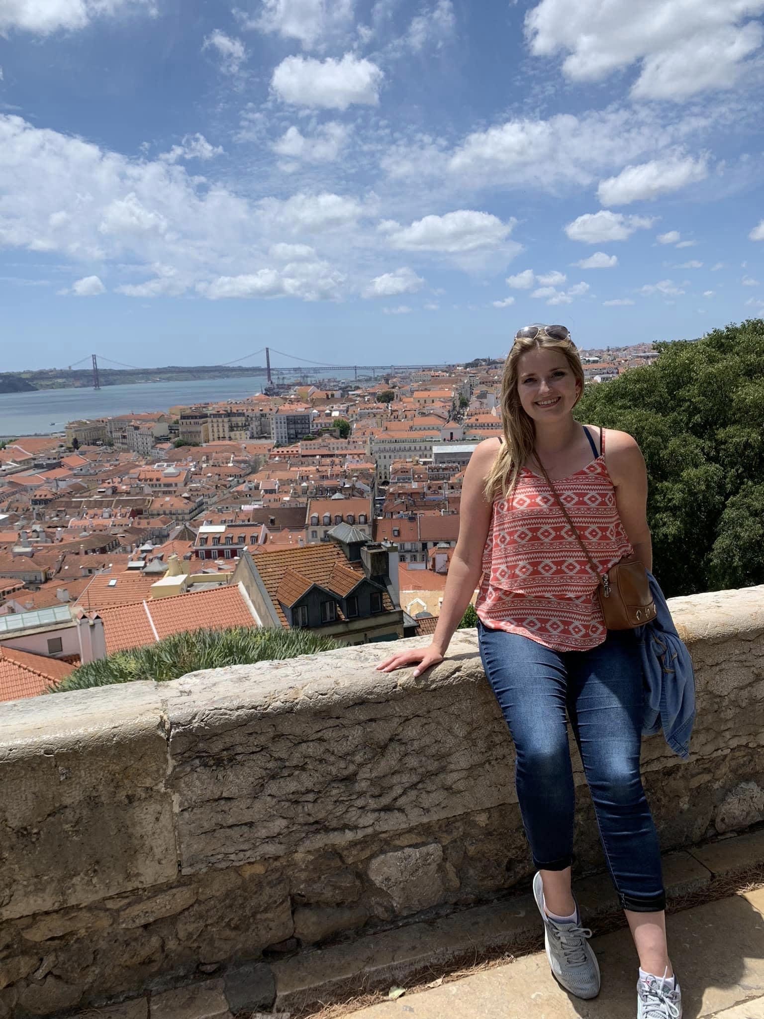 Leah posing in front of a view of sunny Lisbon from Castelo de S. Jorge