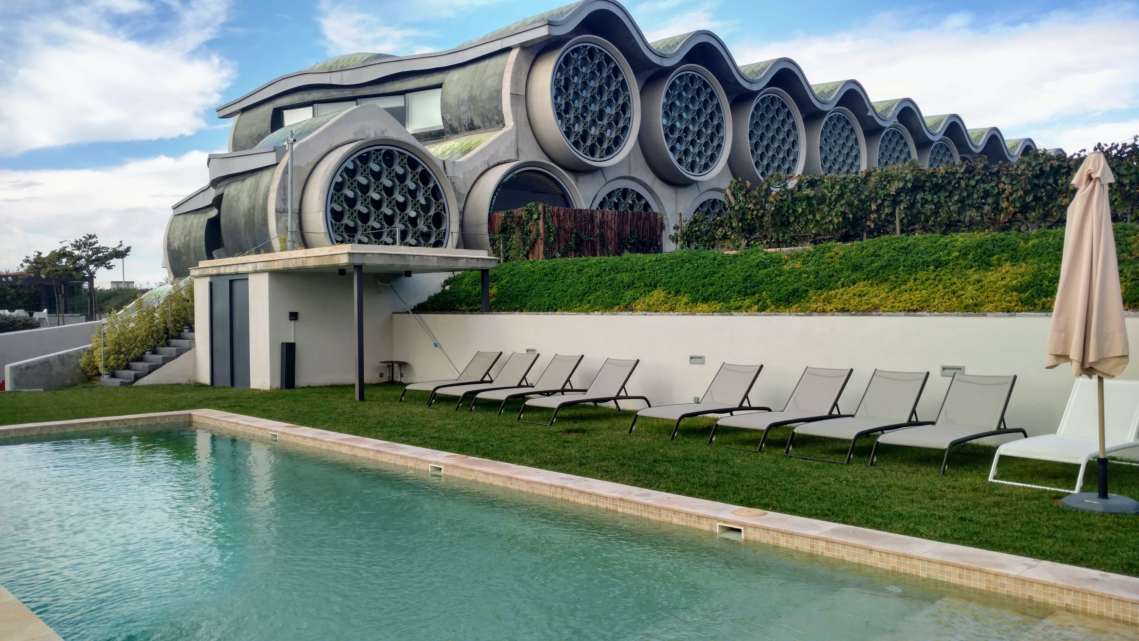 Pool view of Hotel Mastinell on a sunny day with loungers and sun umbrellas.