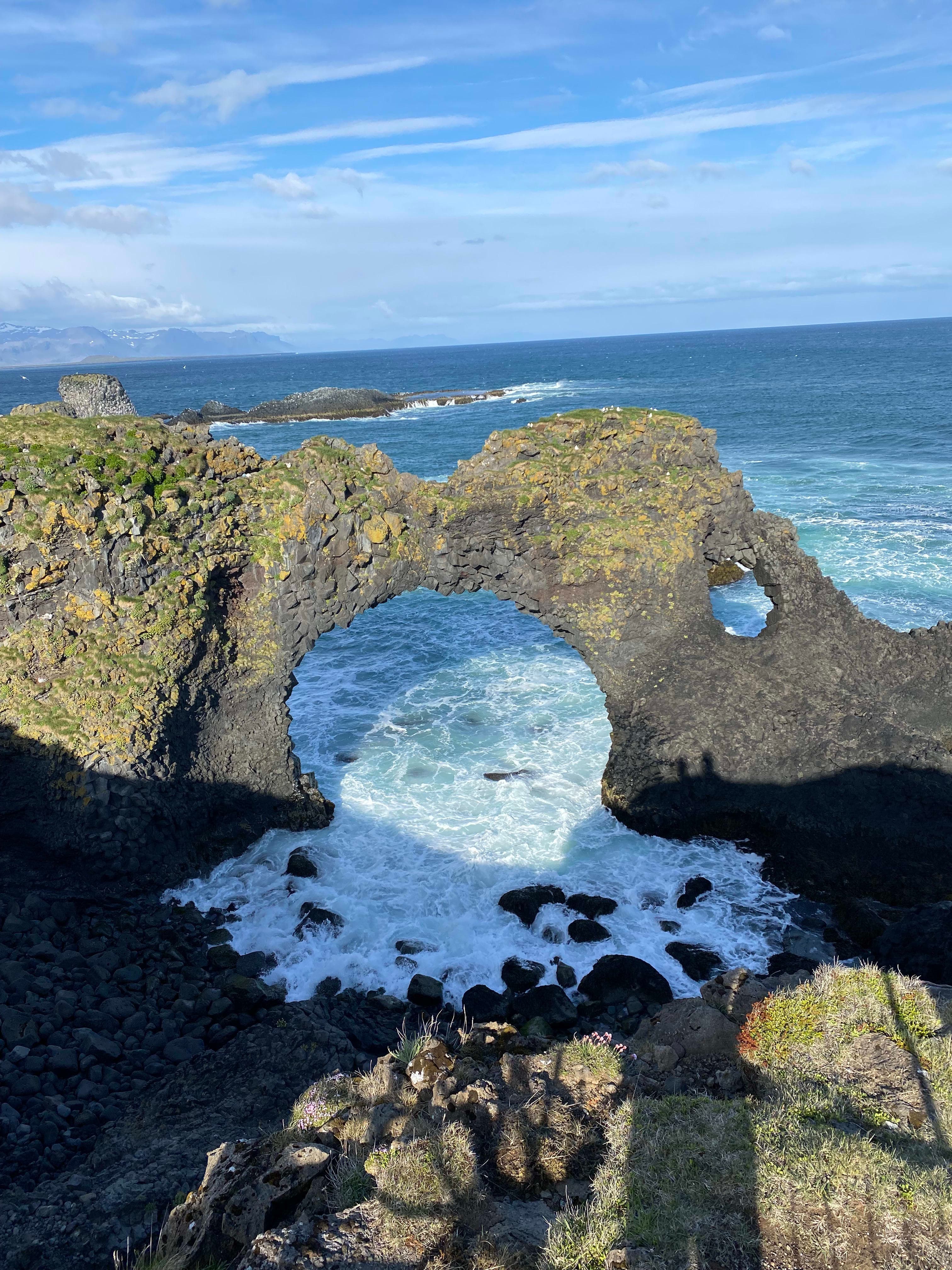 A beautiful stone arch at Gatklettur with the ocean in the distance on a sunny day