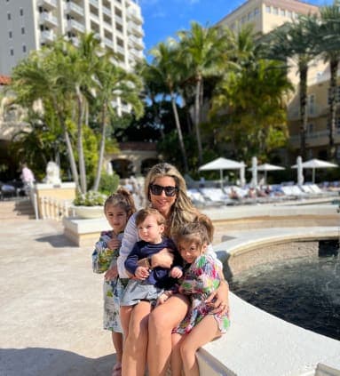 A woman and three children posing in front of a water fountain