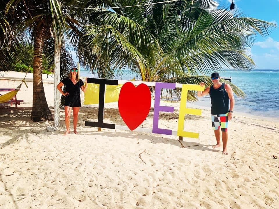 Travel advisor Lisa and male companion posing by an I Love EE sign on a beach