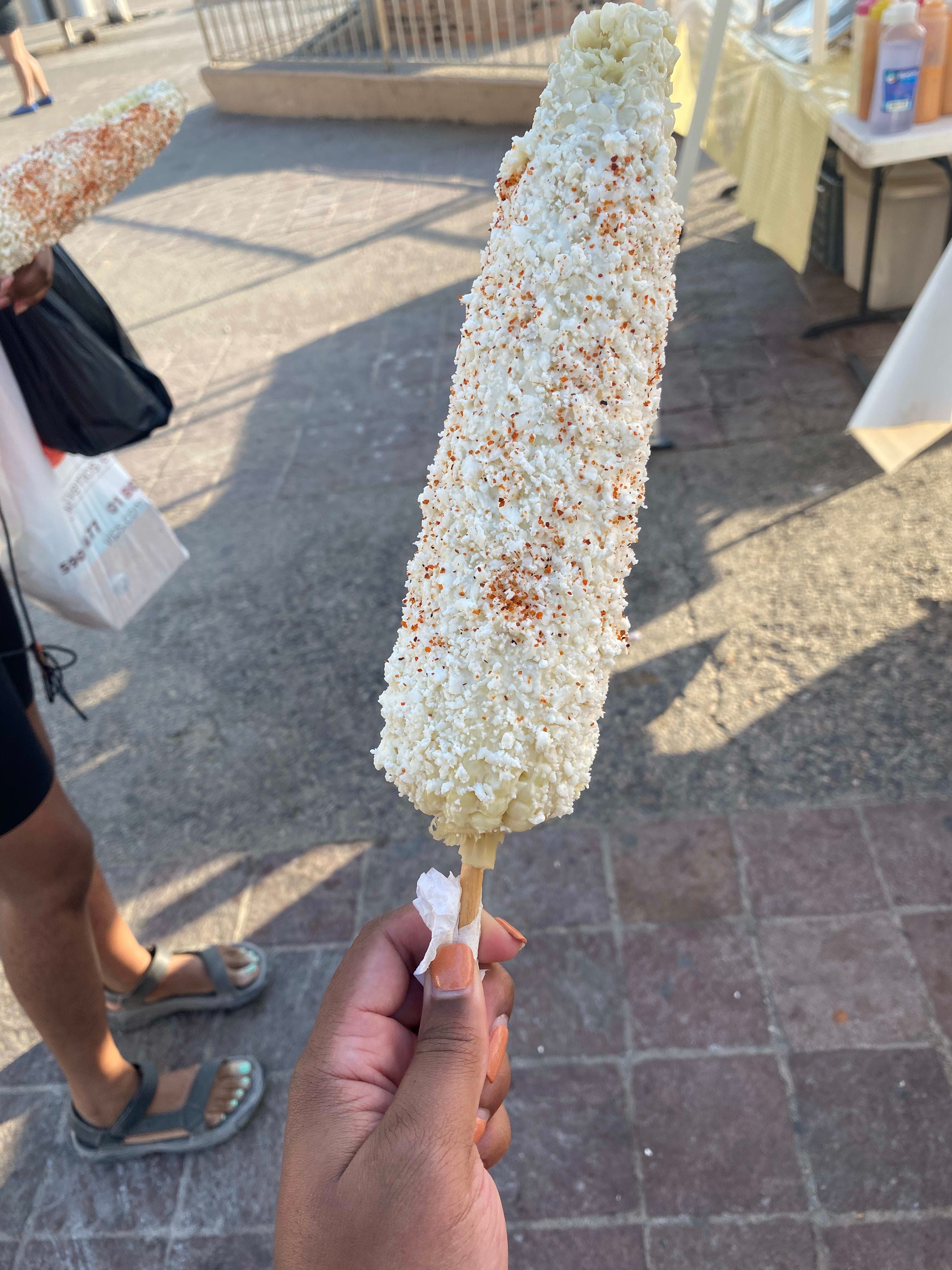 Corn on a stick covered in toppings