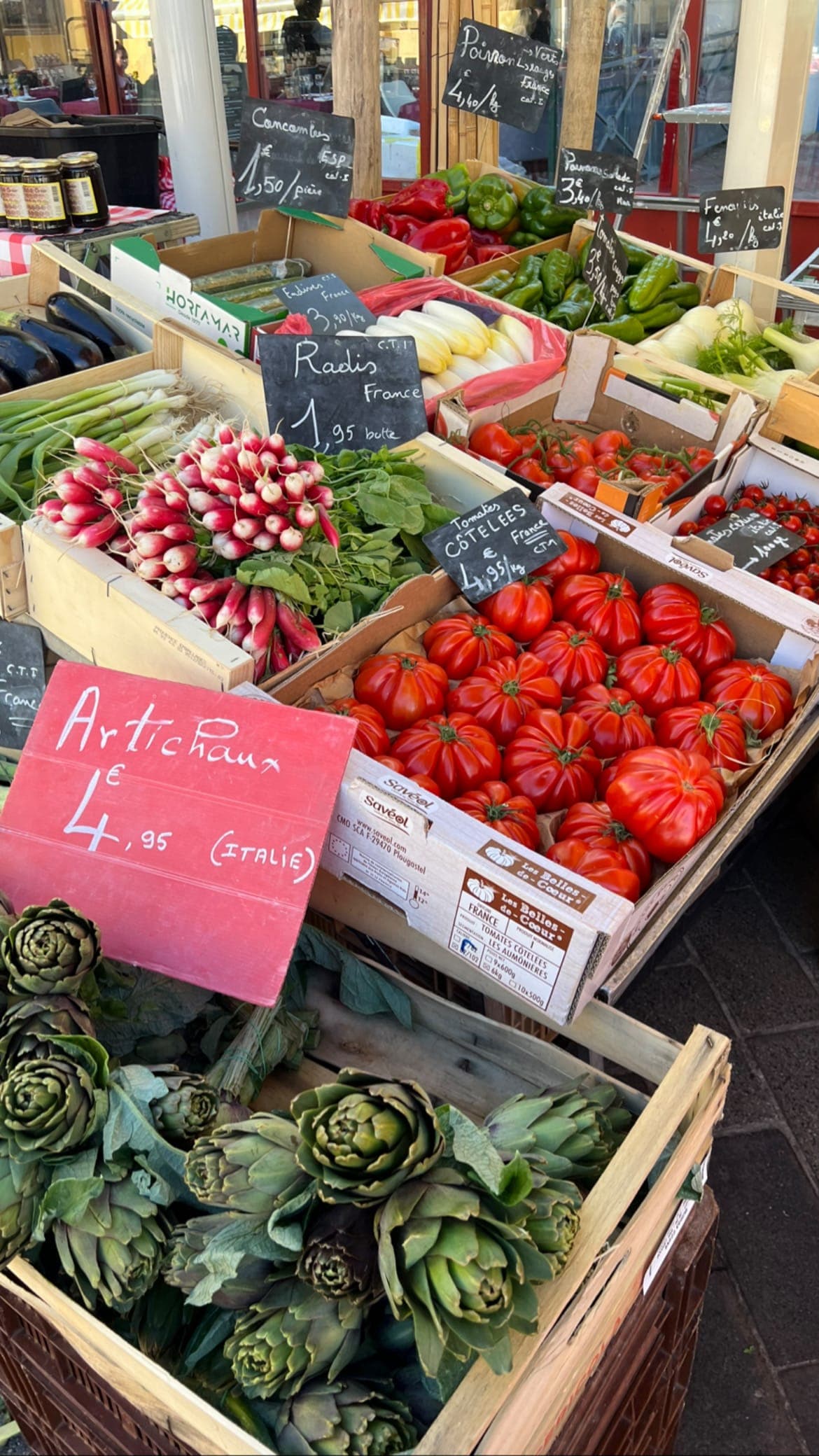 A vendors cart selling fresh produce including tomatoes, artichokes and radish
