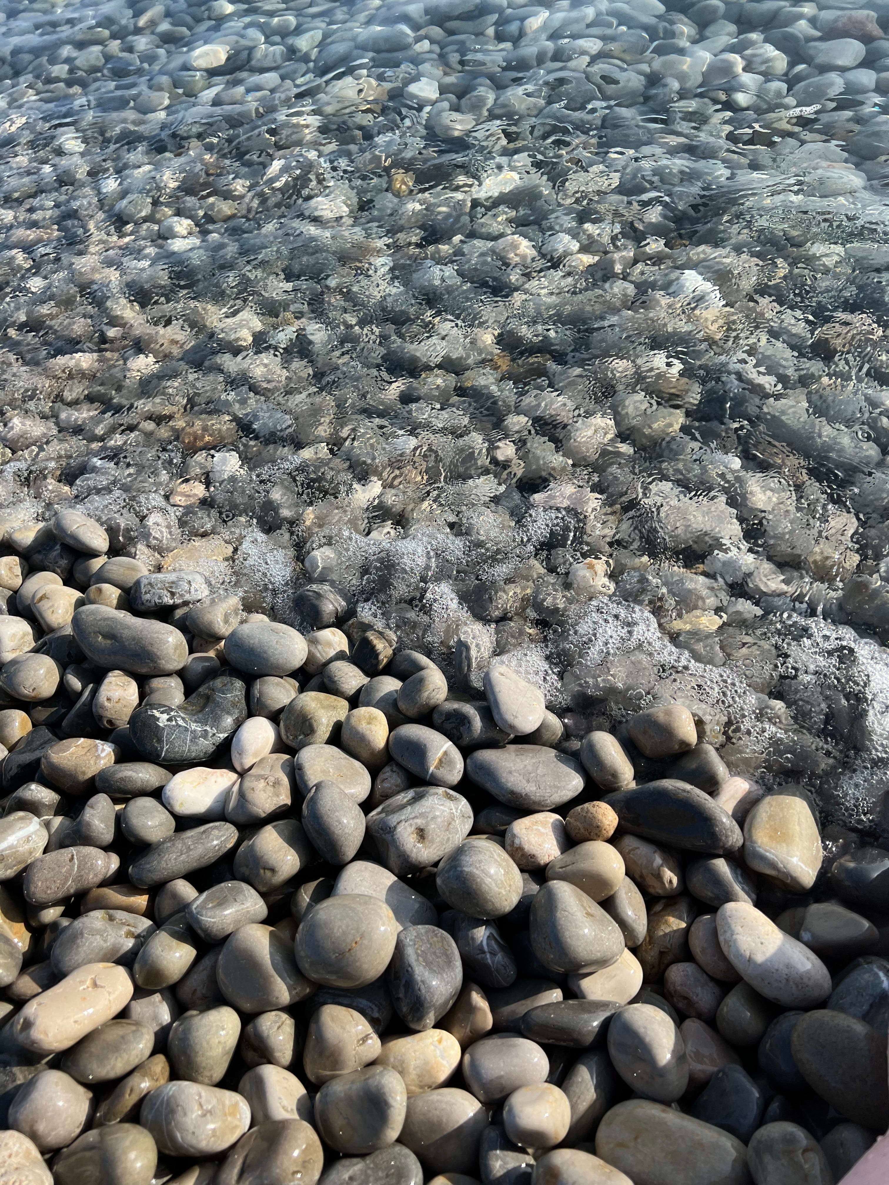 A close up of sea waves crashing on shore full of pebbles