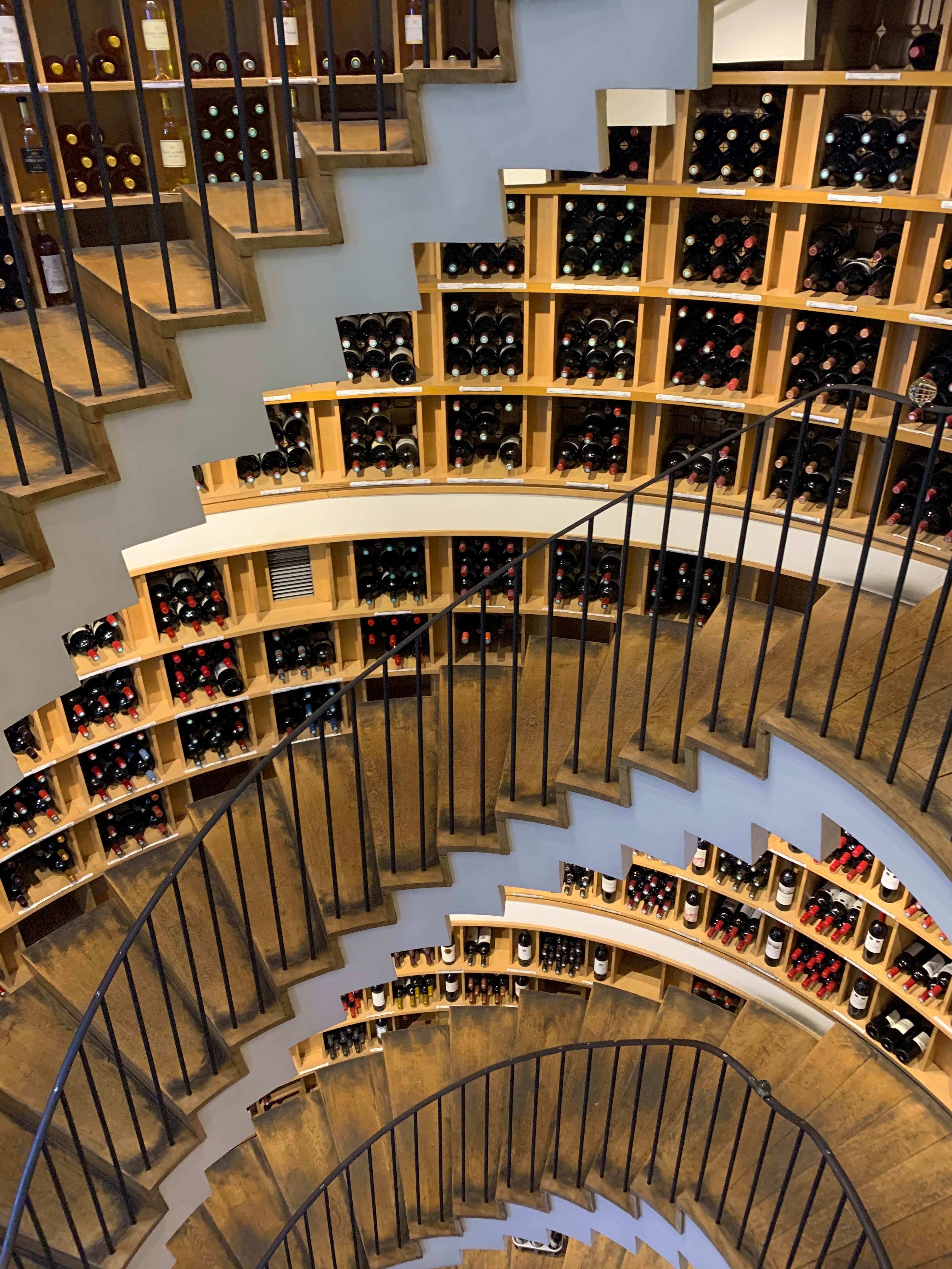 A winding staircase with shelves full of wine on each floor