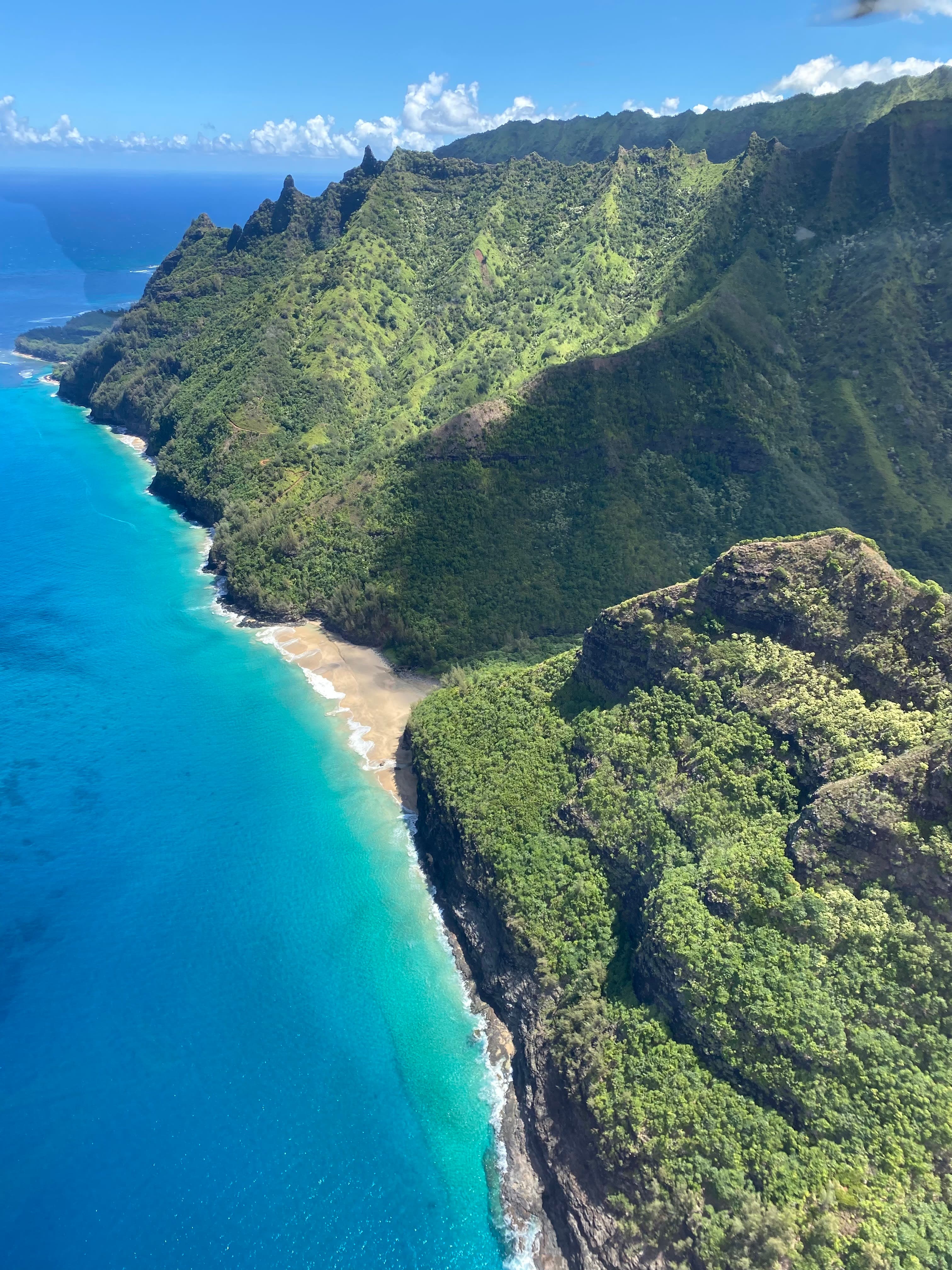 View of the coast with clear blue water of the sea and green hills on the shore