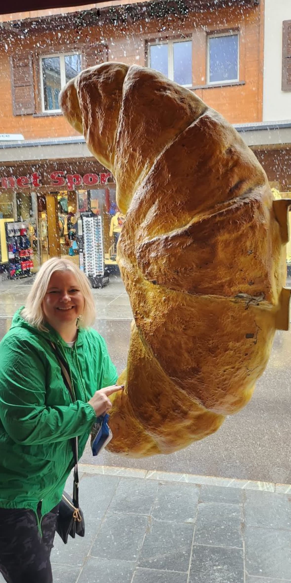 Travel advisor Amy posing for a photo with a giant croissant hanging in the window
