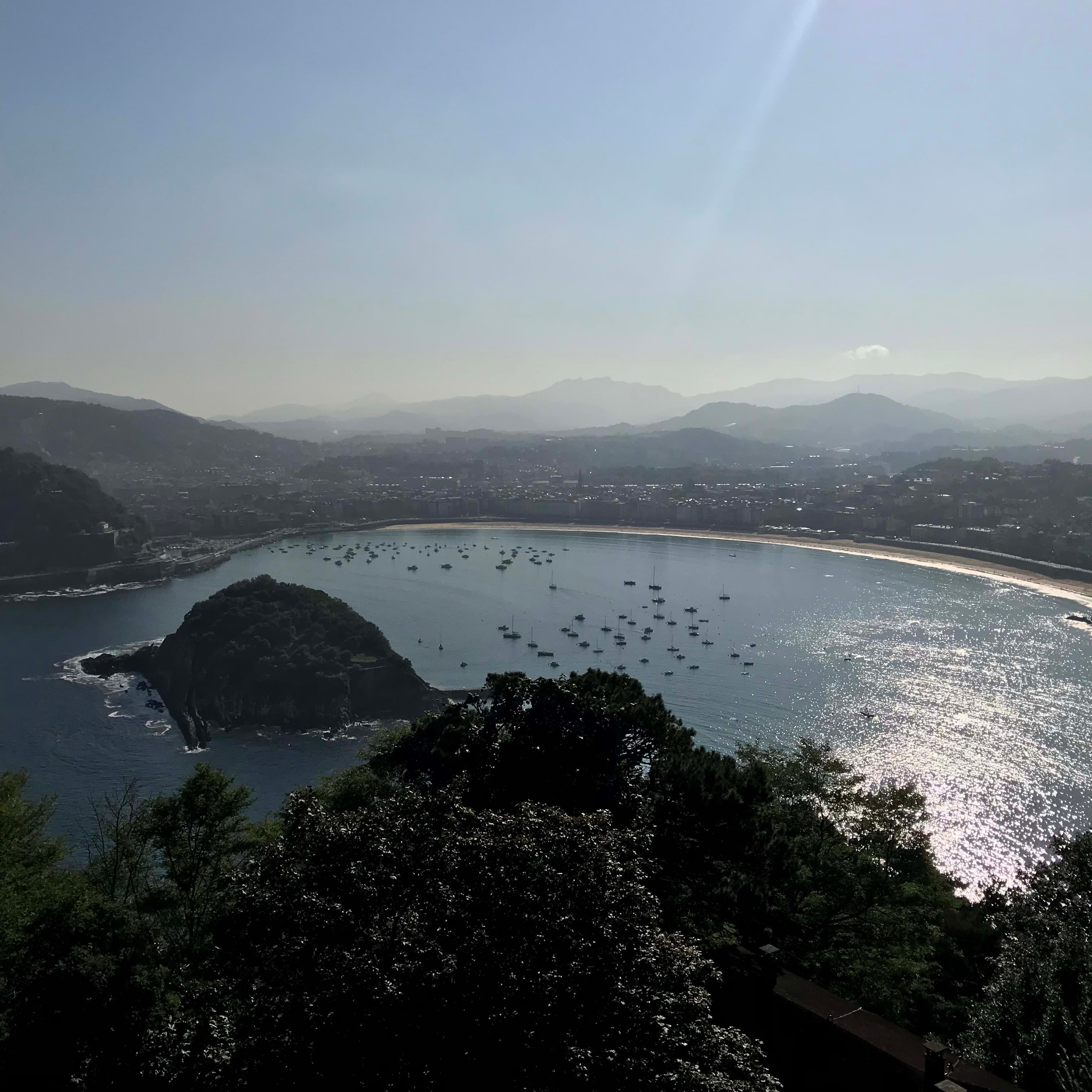 Beautiful view of the bay of San Sebastian, Spain with boats in the ocean, the beach, city and mountains