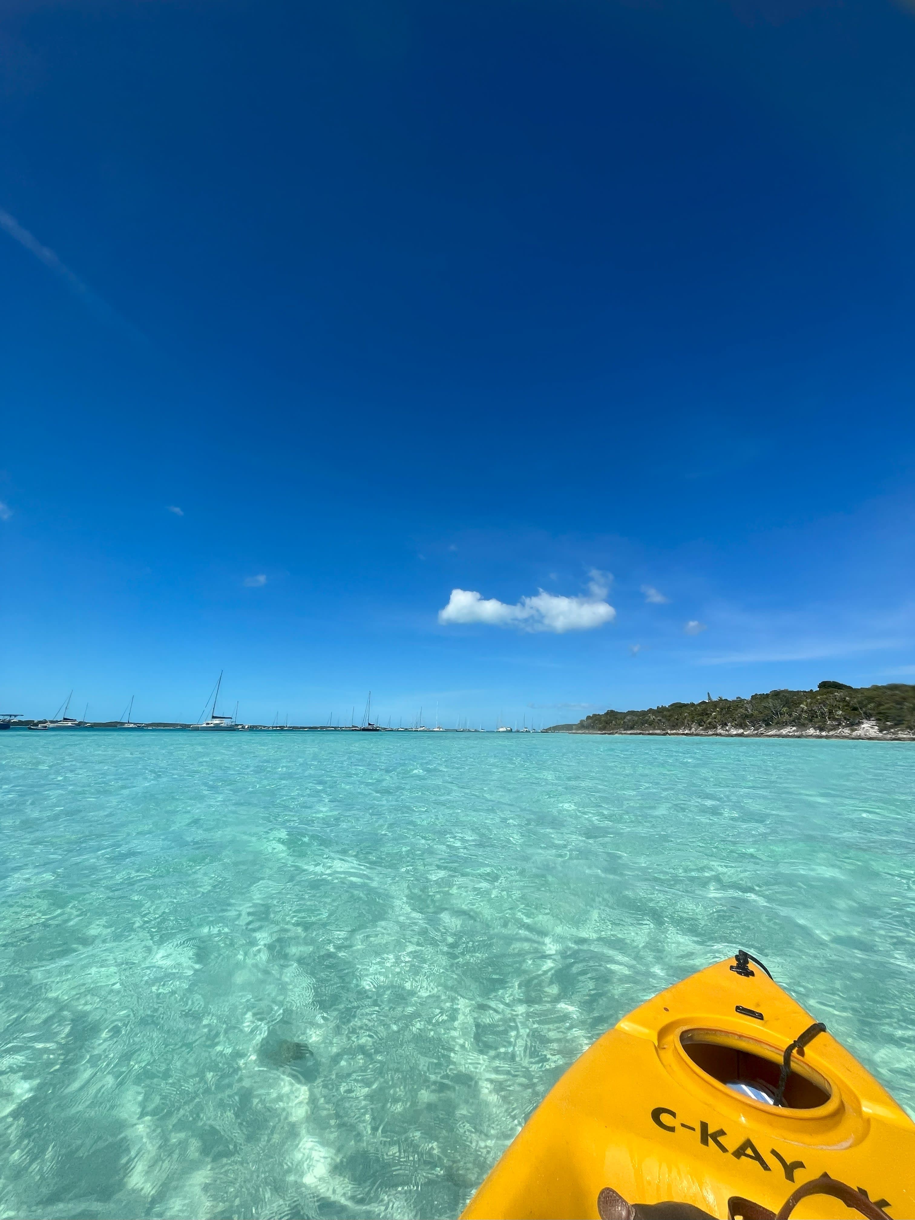 The front part of a yellow kayak in transparent. turquoise ocean