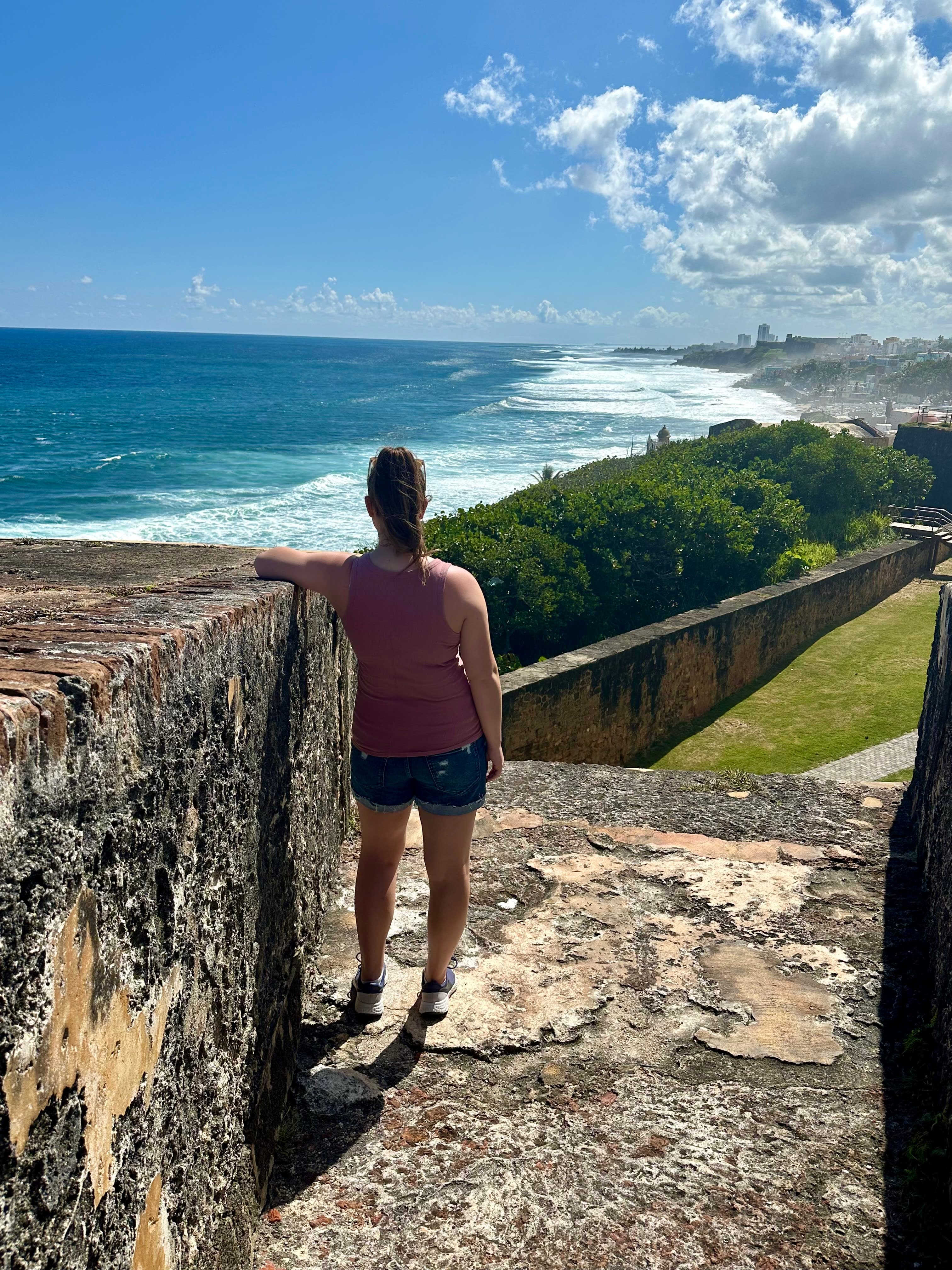 Elizabeth standing on stone steps overlooking the ocean.