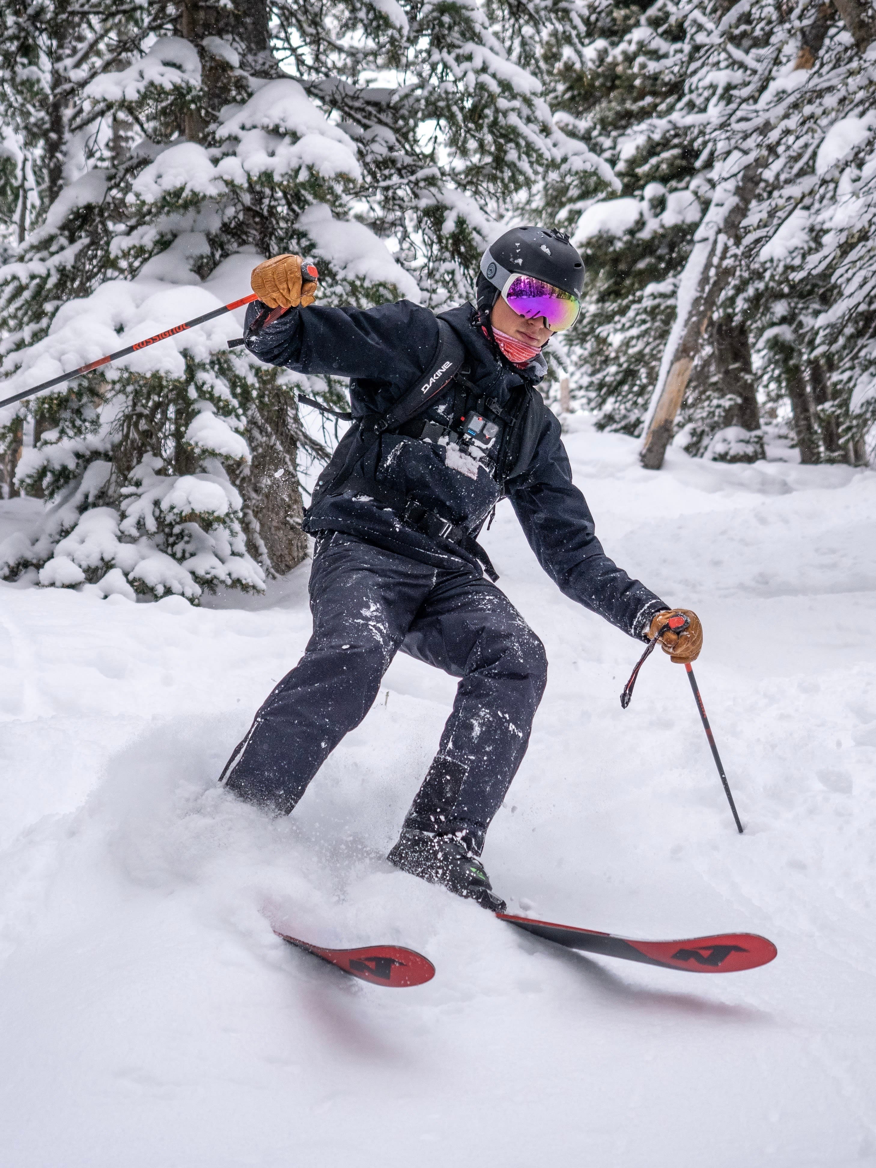 An action shot of Justin Strauss skiing with trees behind him