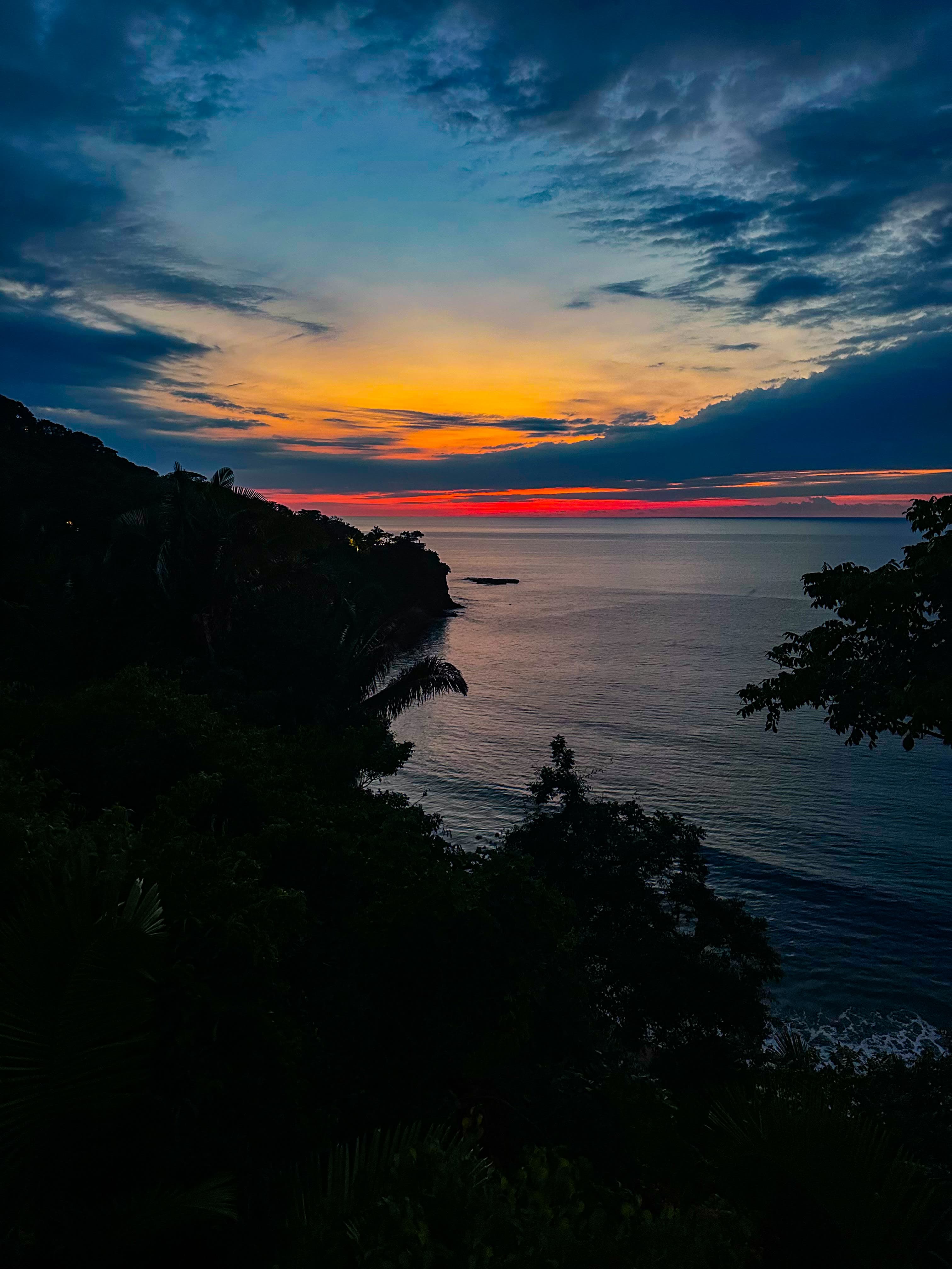 View of the sea from the land at sunset with a cloudy sky
