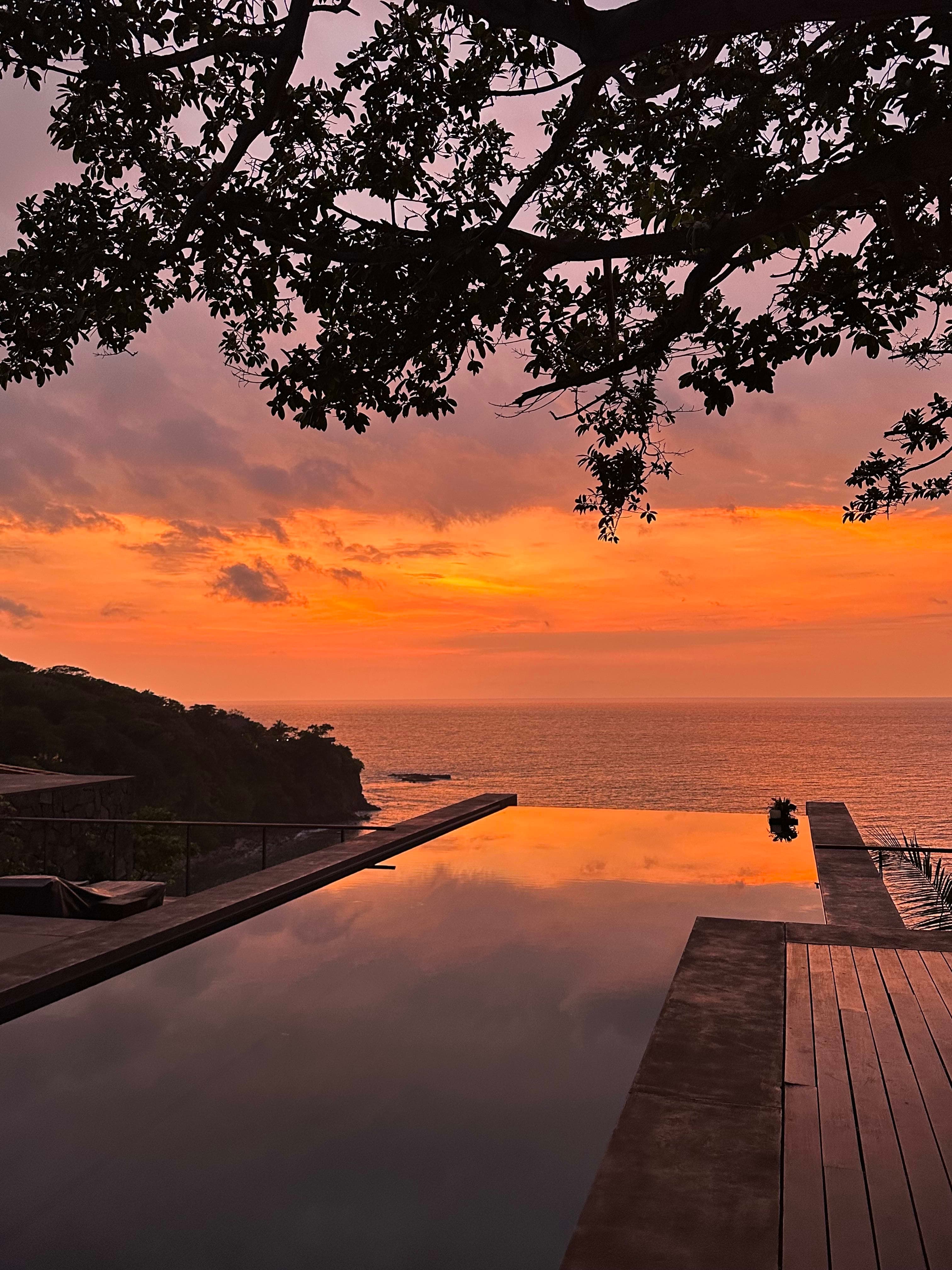 Beautiful view of the pool at sunset with an orange sky