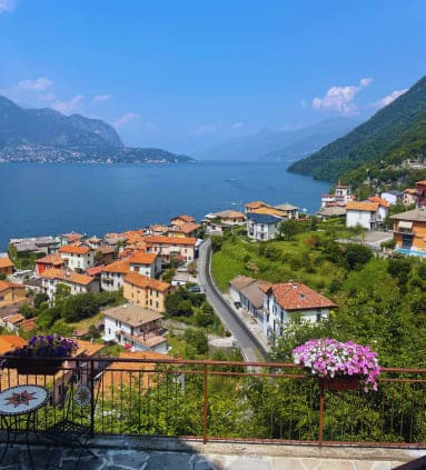 View of Lake Como in Italy from a hotel balcony, with a flower box planter and table
