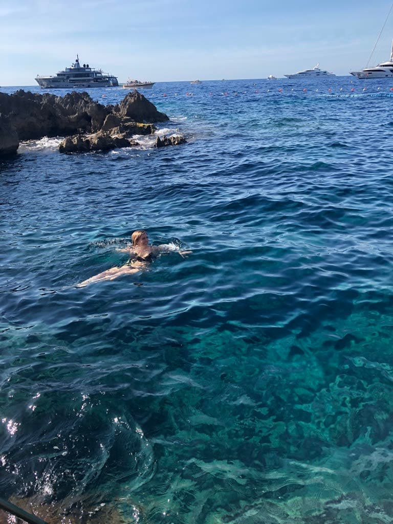 Stefanie swimming in the sea, with several boats in view in the distance