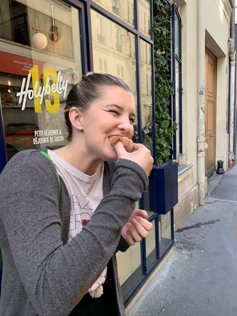 Stefanie eating a doughnut standing outside a bakery