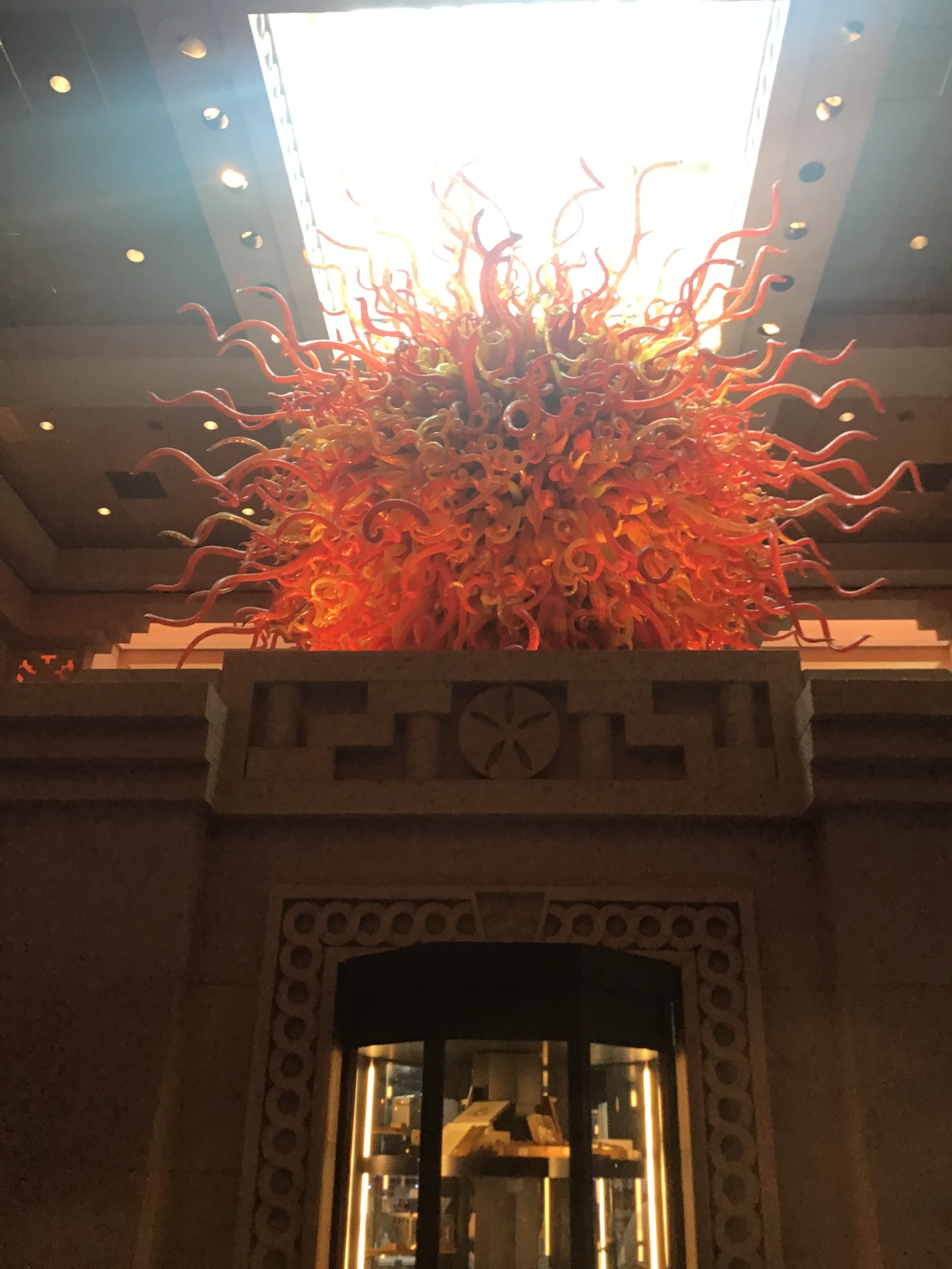 Image of a large orange sculpture resembling the sun indoors under a bright light