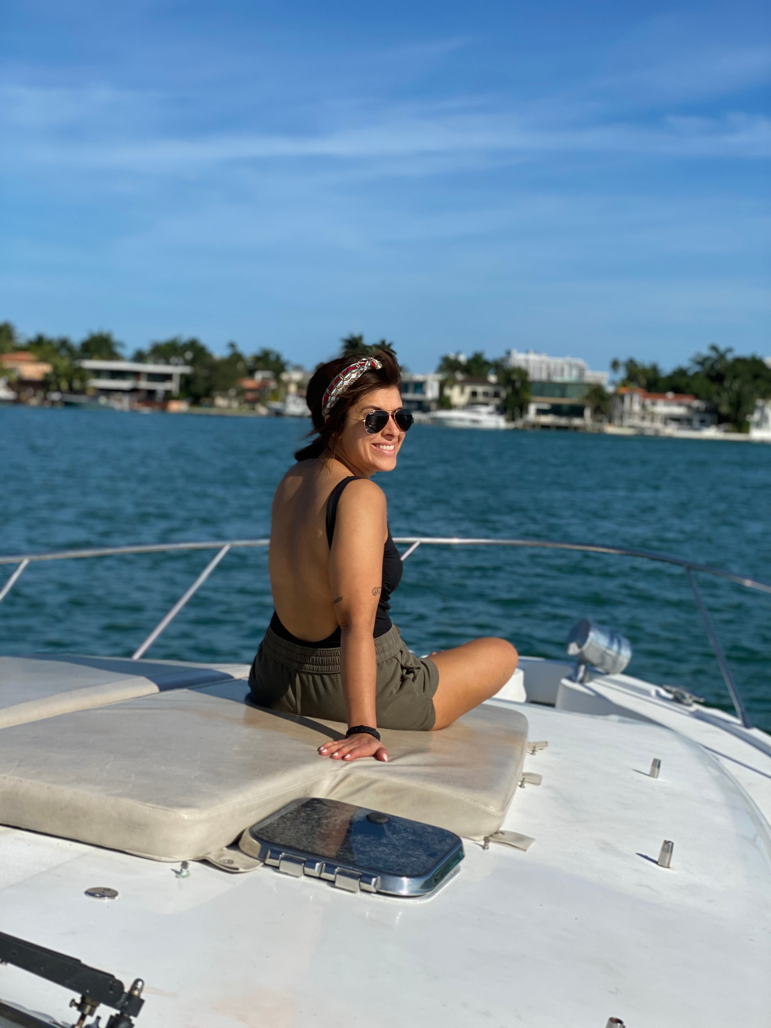 Picture of Leslie sitting in a boat in a bathing suit and shorts