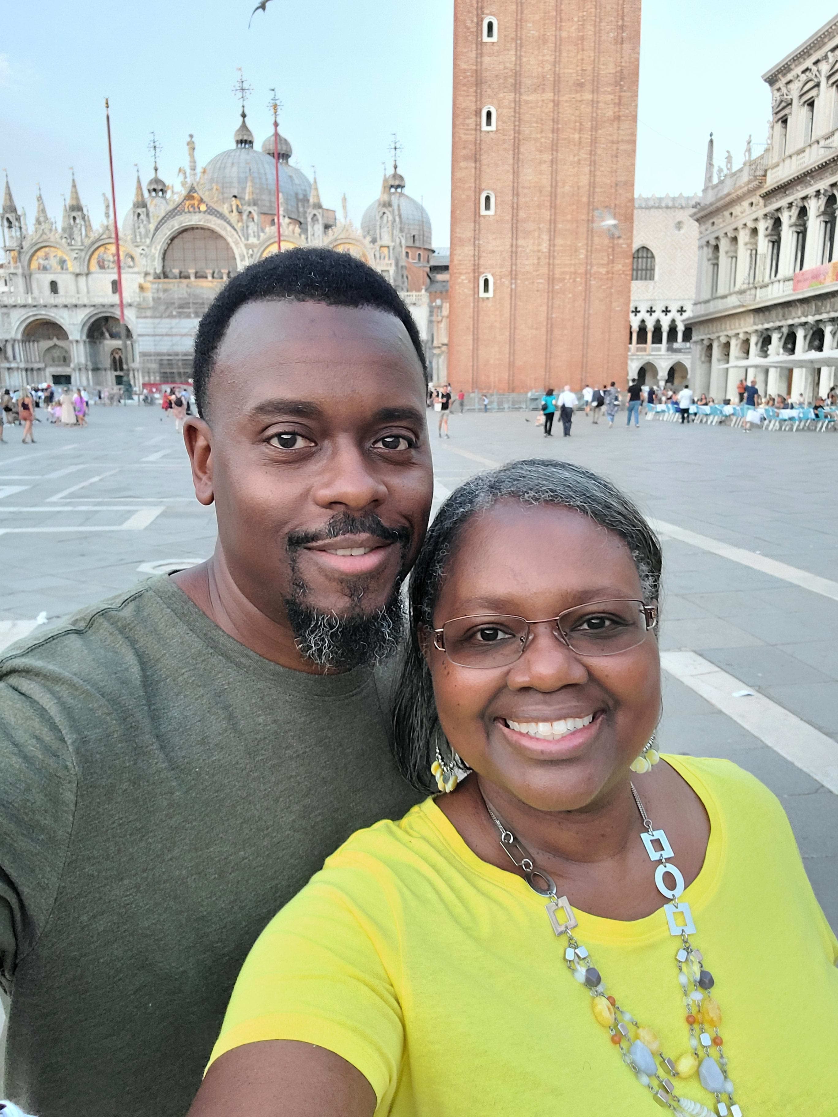 Couple taking a selfie in a large square in front of old buildings