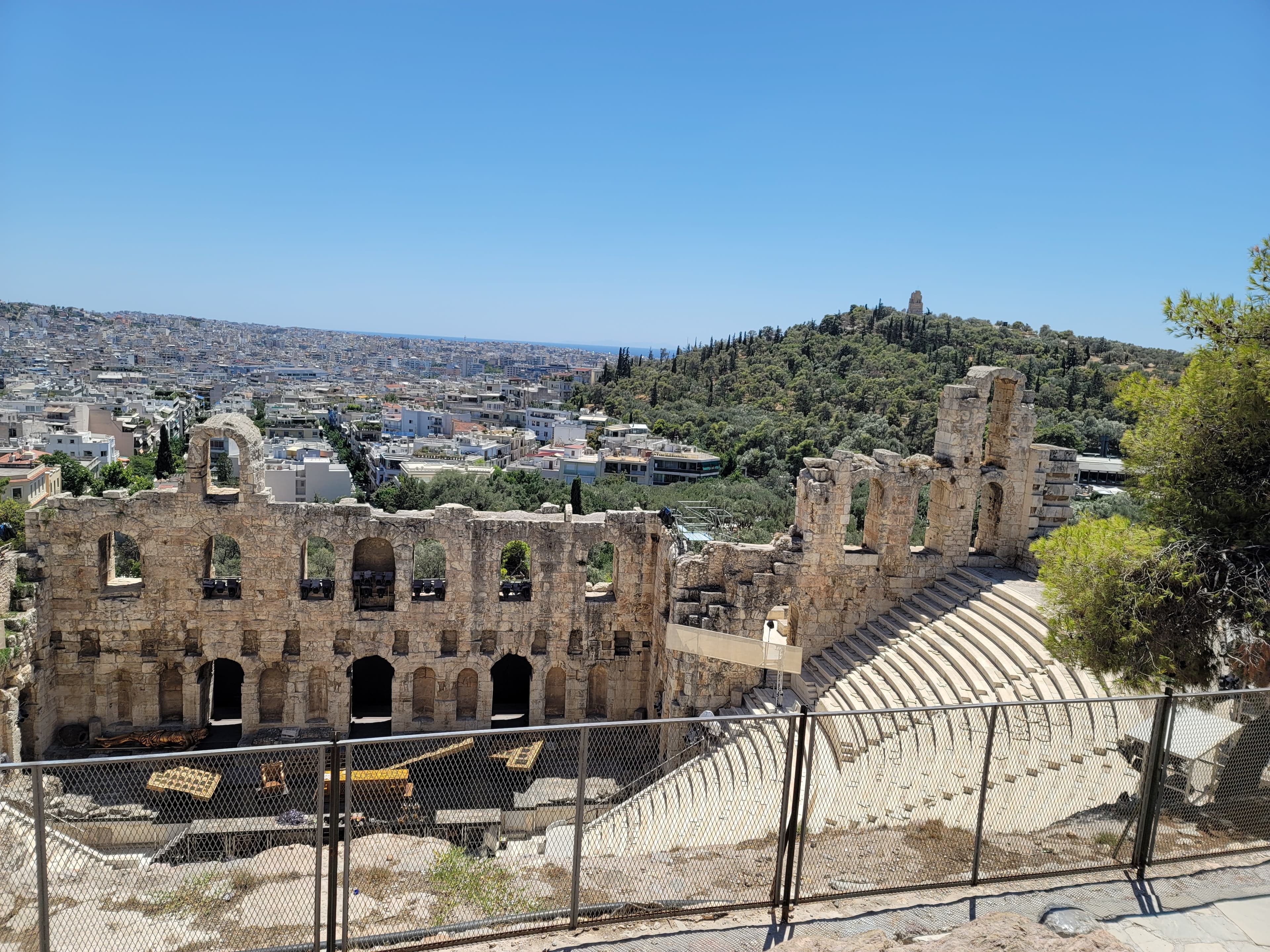 View of the ancient ruins of Odeon of Herodes Atticus with a city view behind
