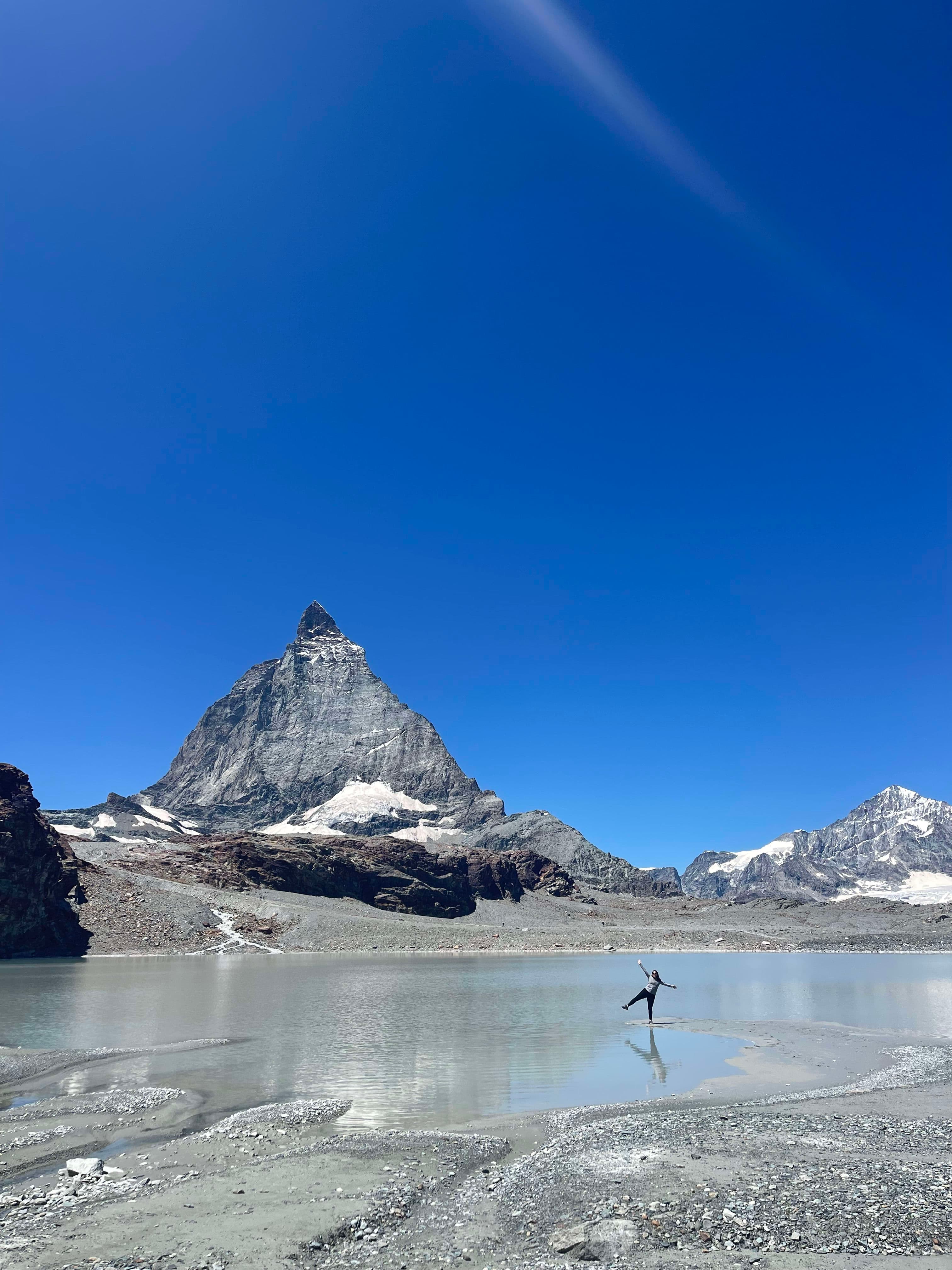 A mountain next to a shallow gravel lake on a clear day