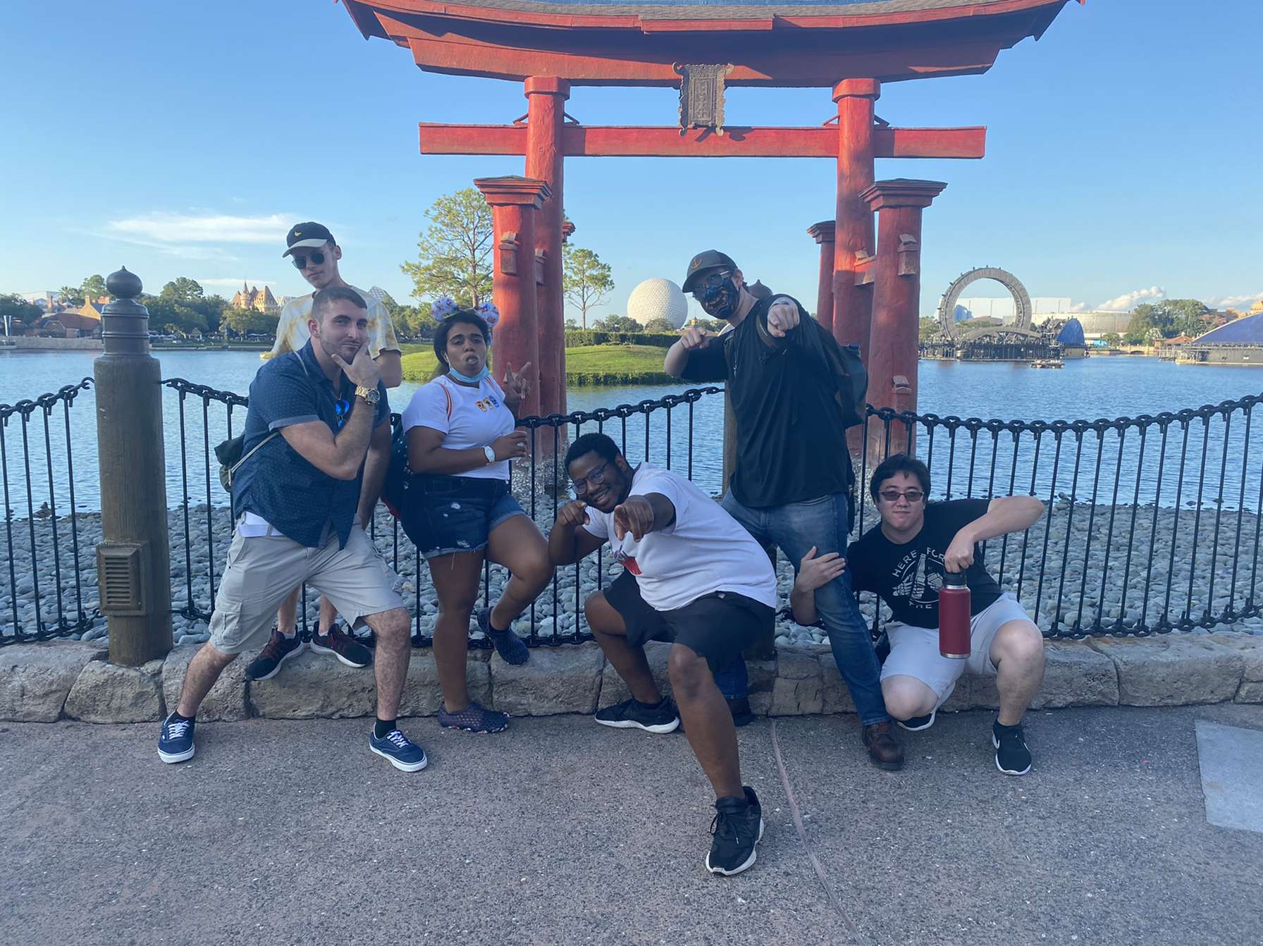 William posing for a picture with friends in front of a red gate on a lake