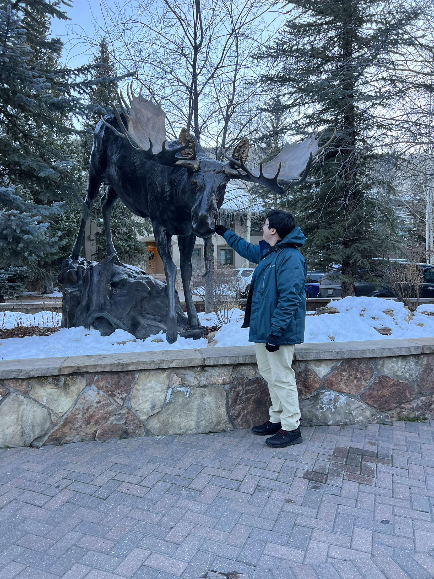 William with a moose sculpture in a snowy town square