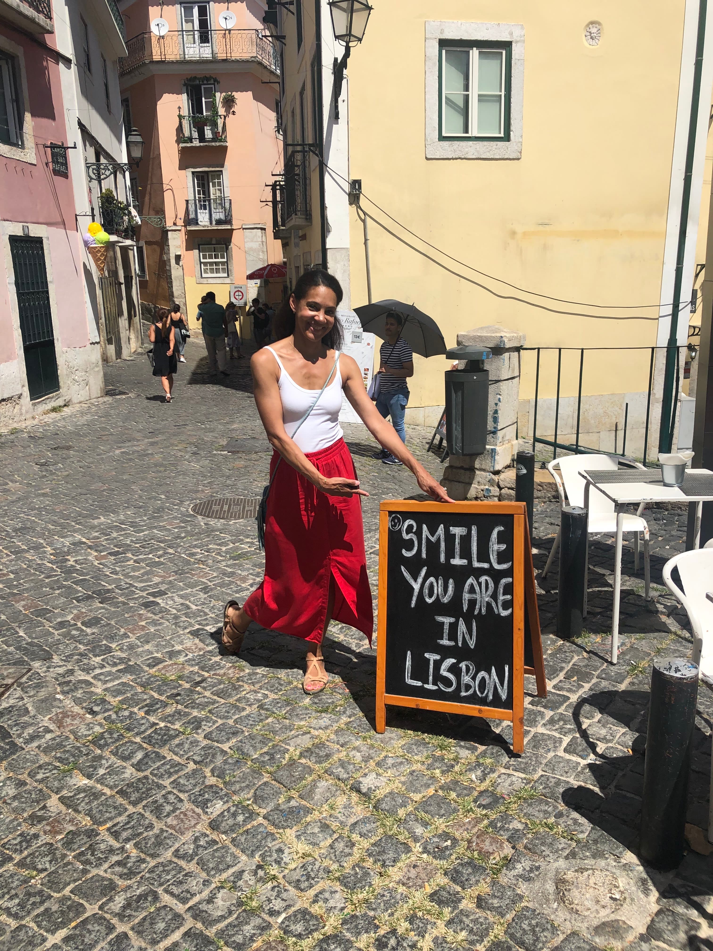 Picture of Michaelyn in Lisbon street next to a sign that says "smile you're in Lisbon"