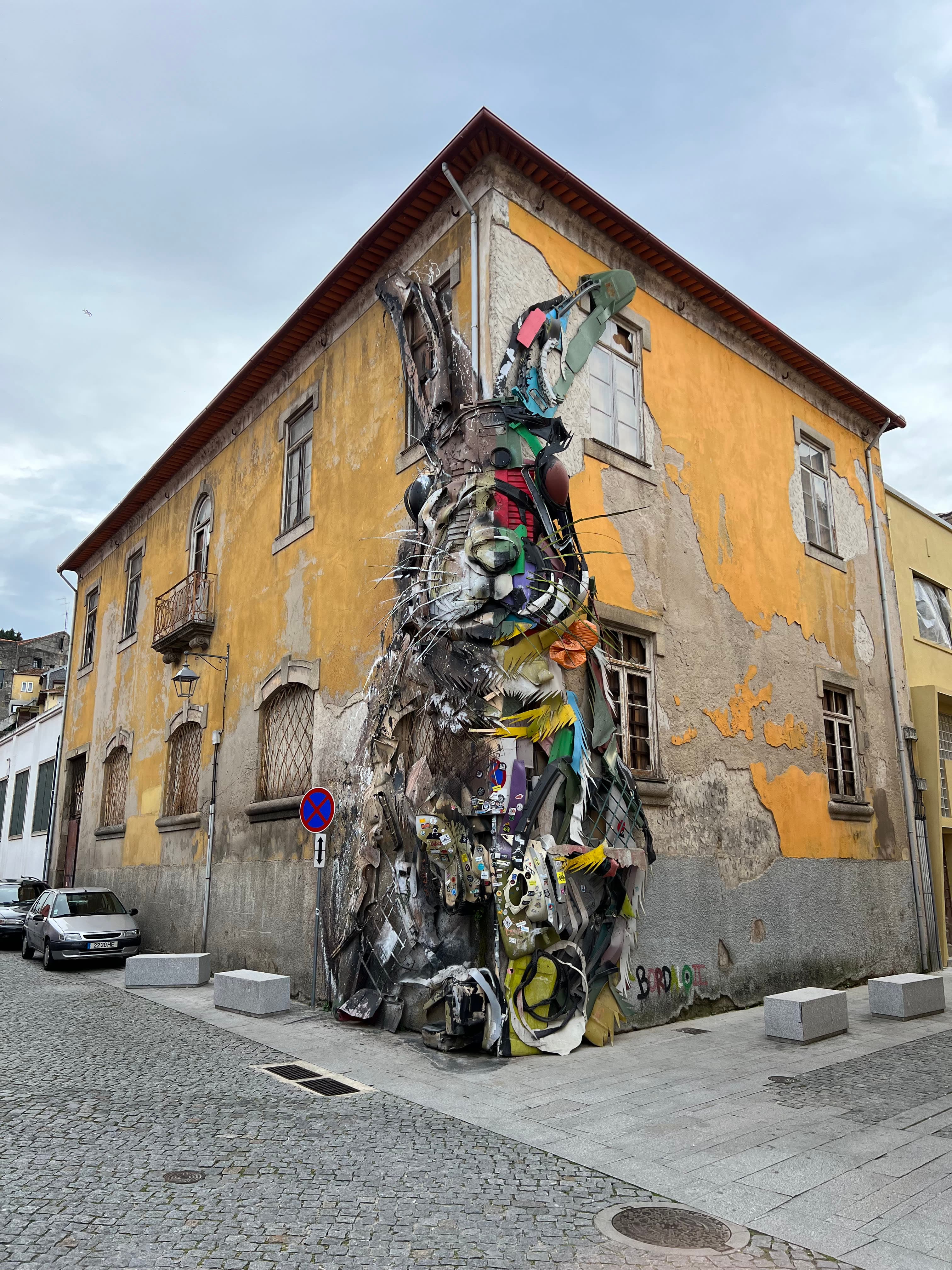 Beautiful view of art piece Half Rabbit by Bordalo II in front of a yellow building