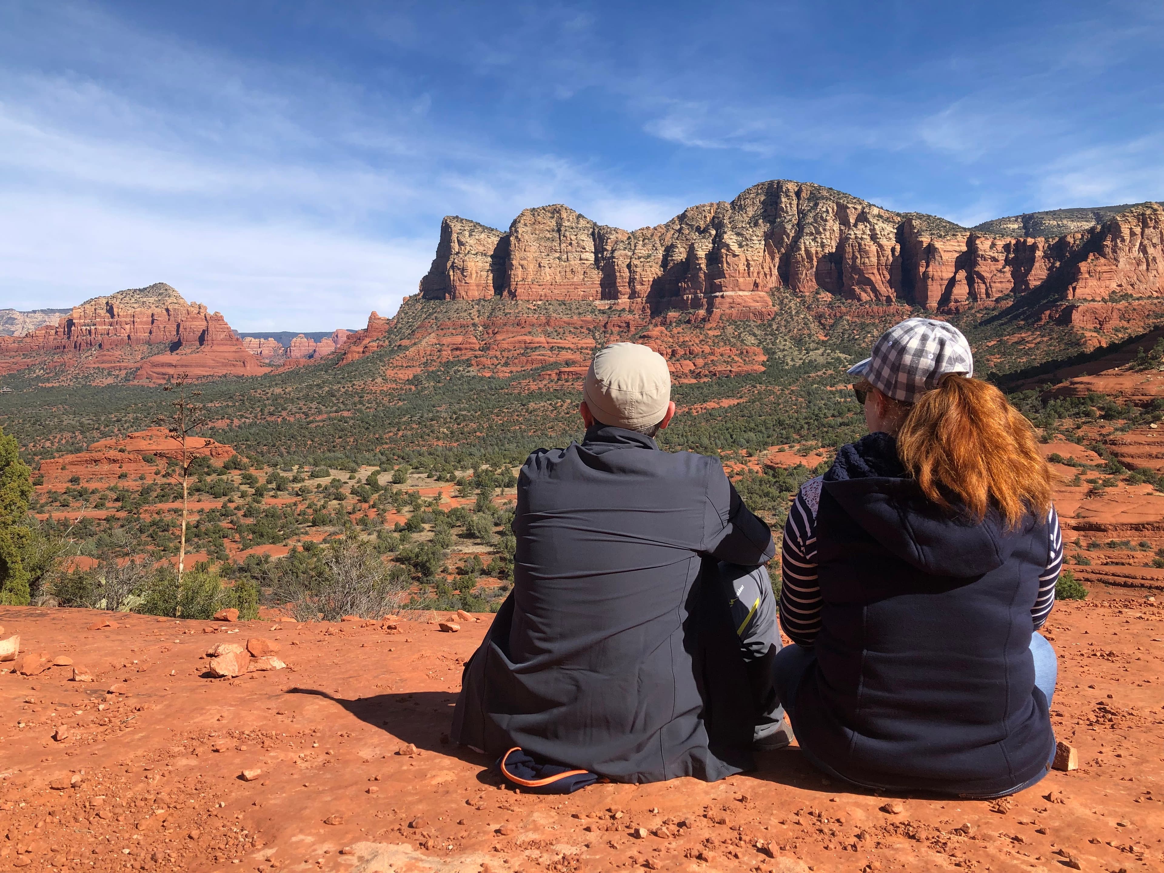 Angela and a man sitting on red rocks overlooking the Arizona desert.