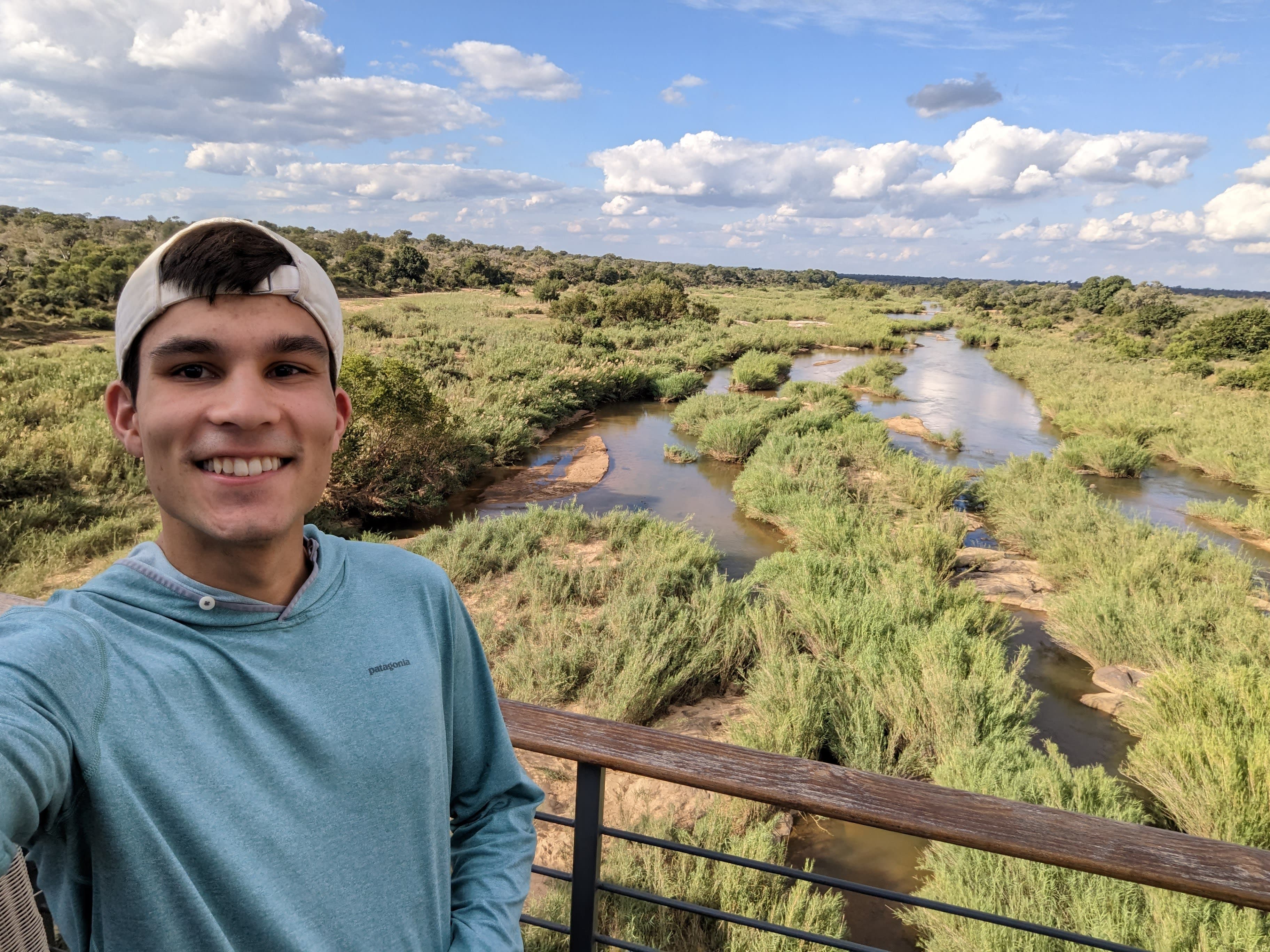 Travel advisor Jackson standing on a balcony overlooking a beautiful view of a green valley with streams