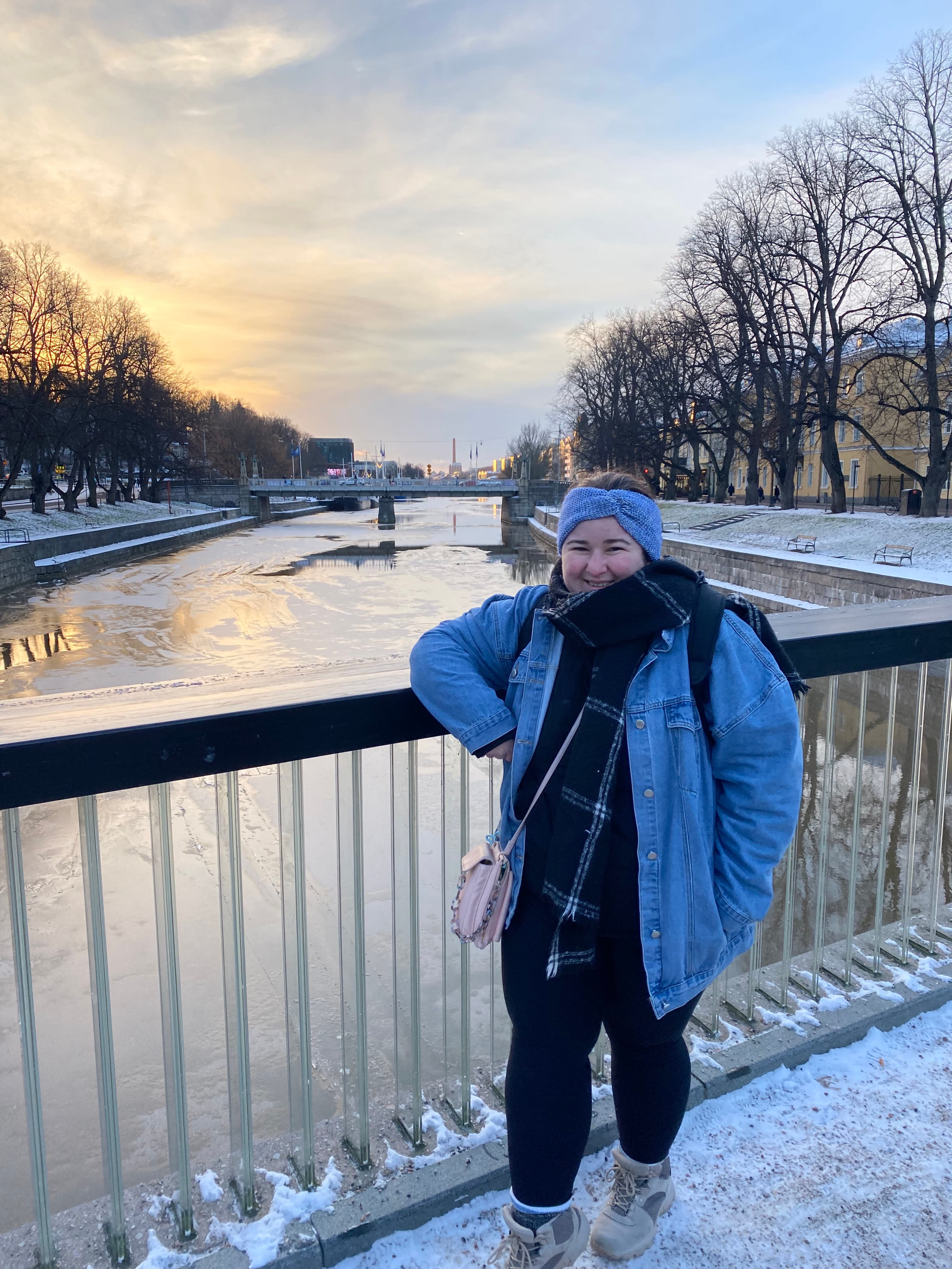 Erika standing on a bridge on Aura River in the winters with snow visible on the ground