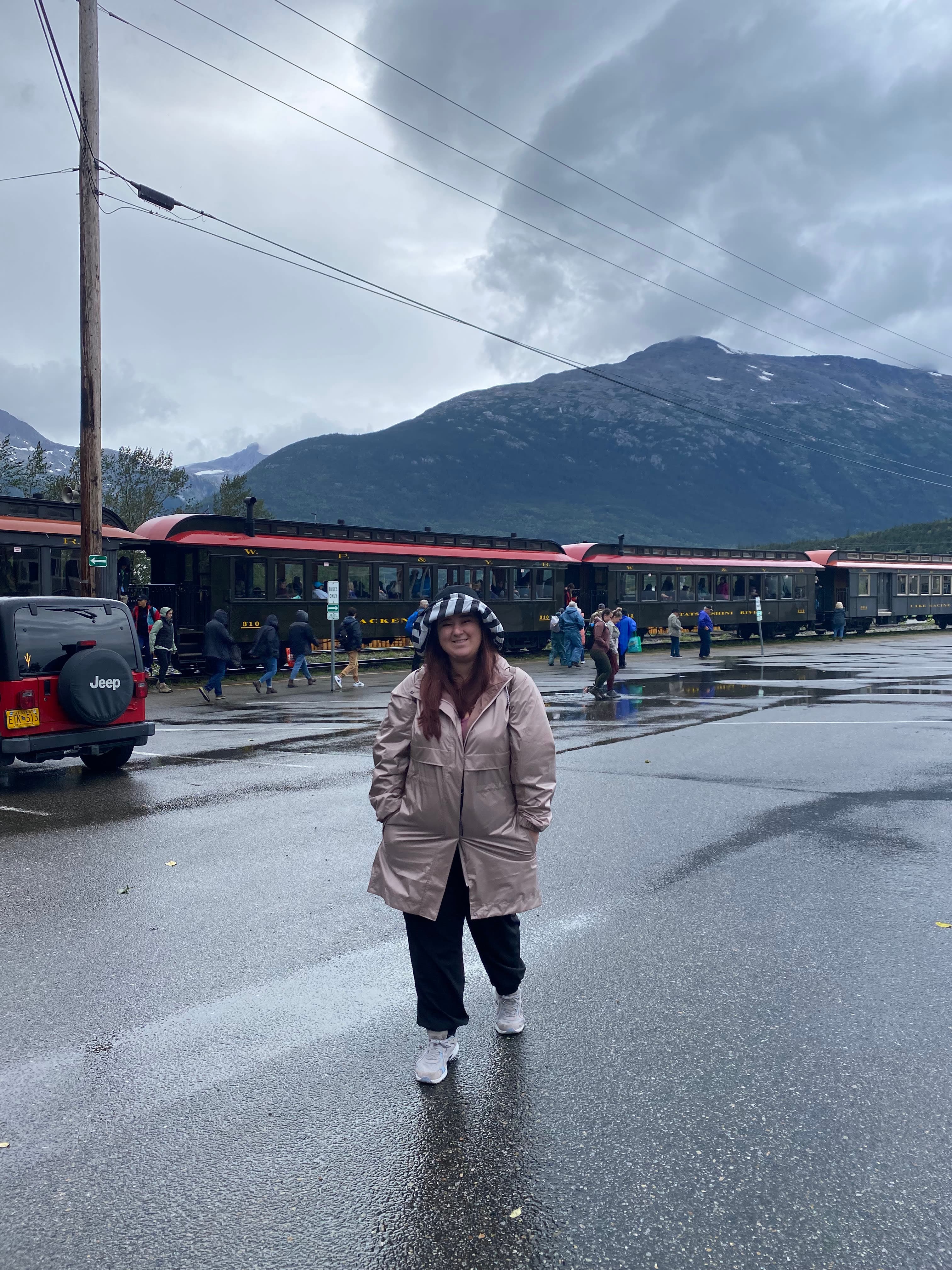 Erika standing on the road ready to board the train on a rainy day