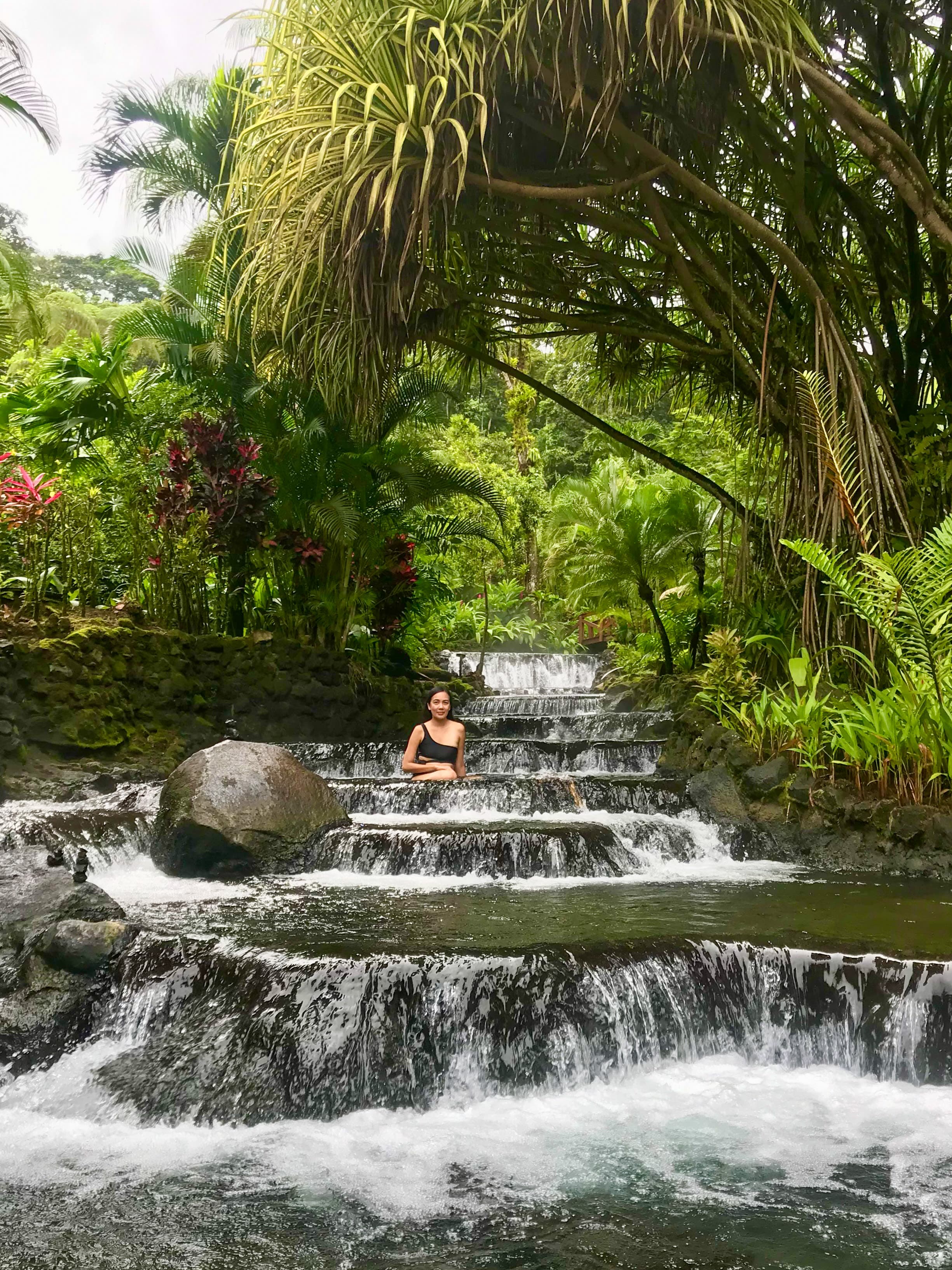Pam sitting on the steps of a waterfall surrounded by beautiful greenery